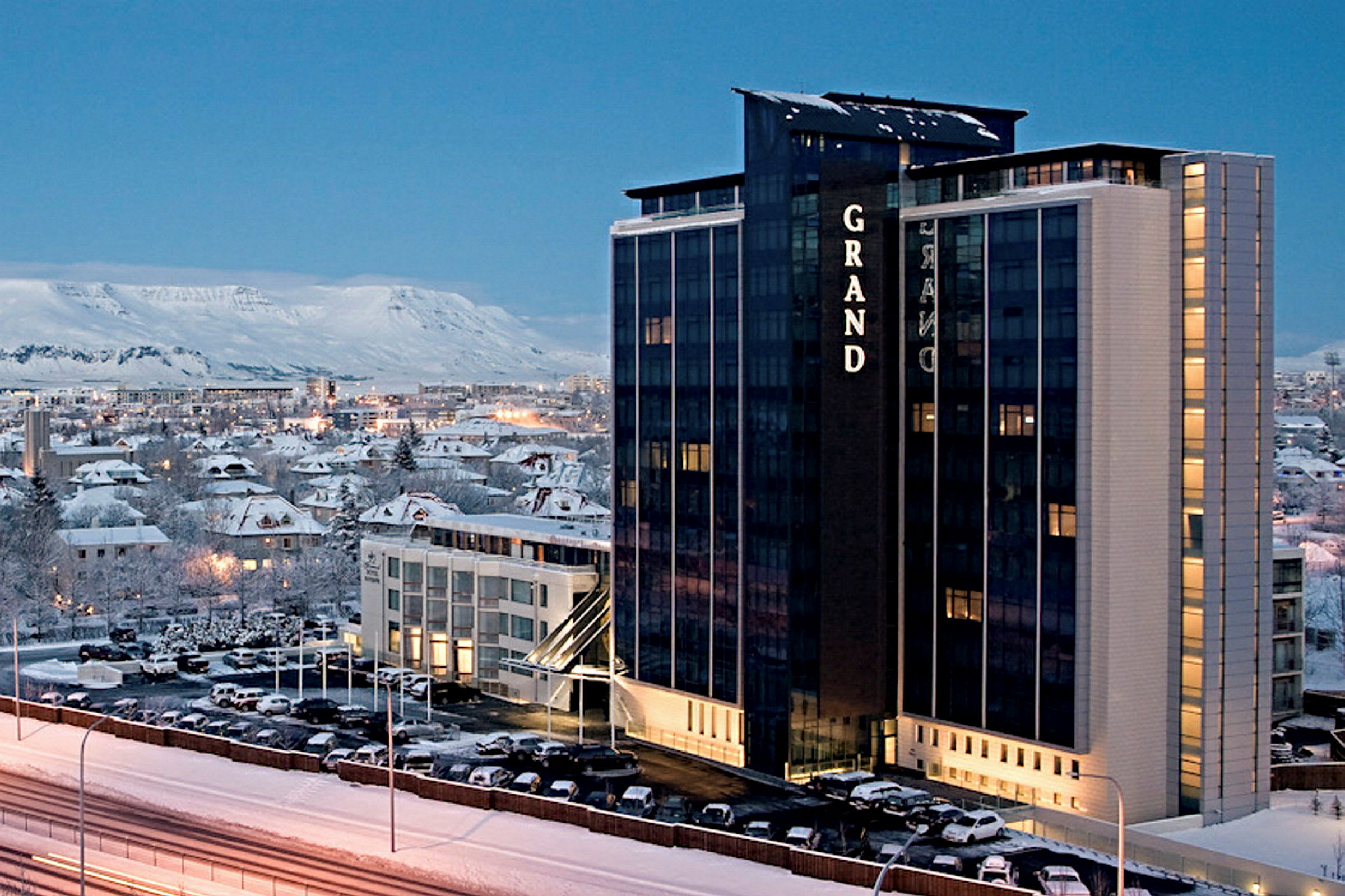Et højhus hotel i vintermiljø med en by og bjerge i baggrunden. (AI-genereret tekst)