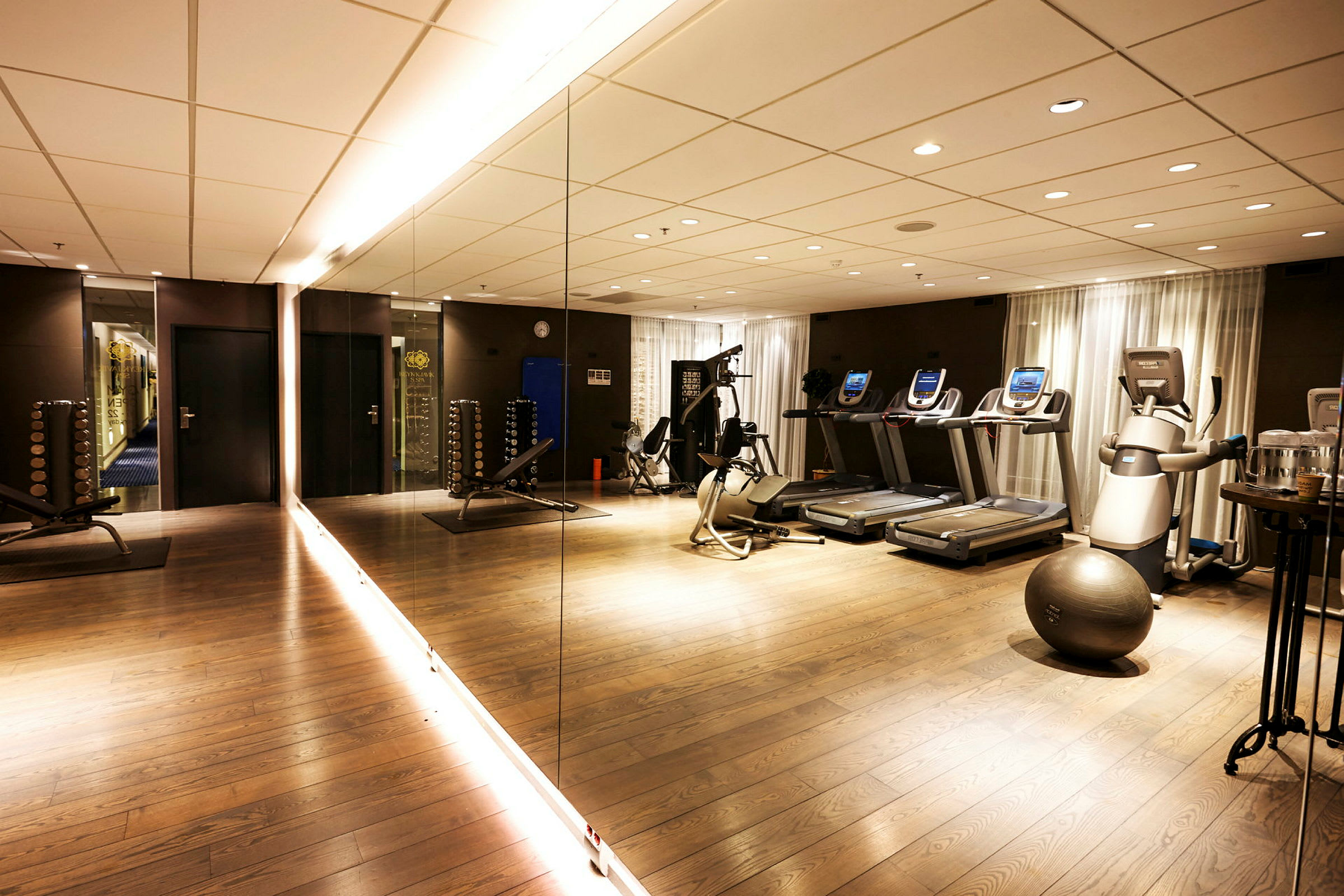 Fitnesscenter med spejlvæg, træningsmaskiner og fitnessudstyr. (AI-genereret tekst)