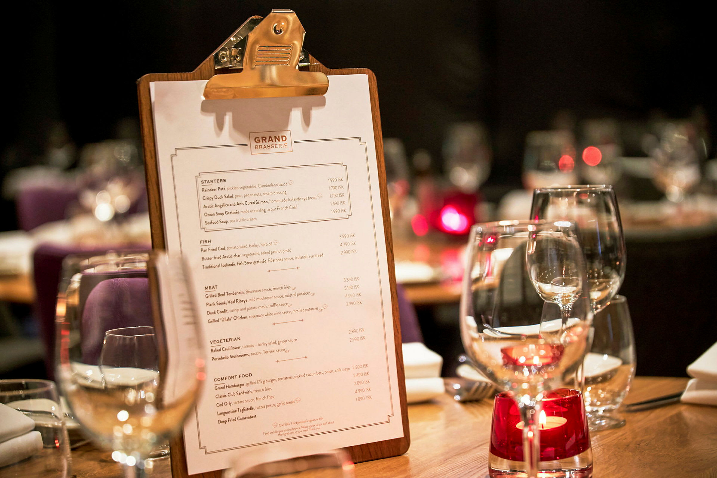Et bord på en restaurant med en menu på en clipboard og glas med borddekoration. (AI-genereret tekst)