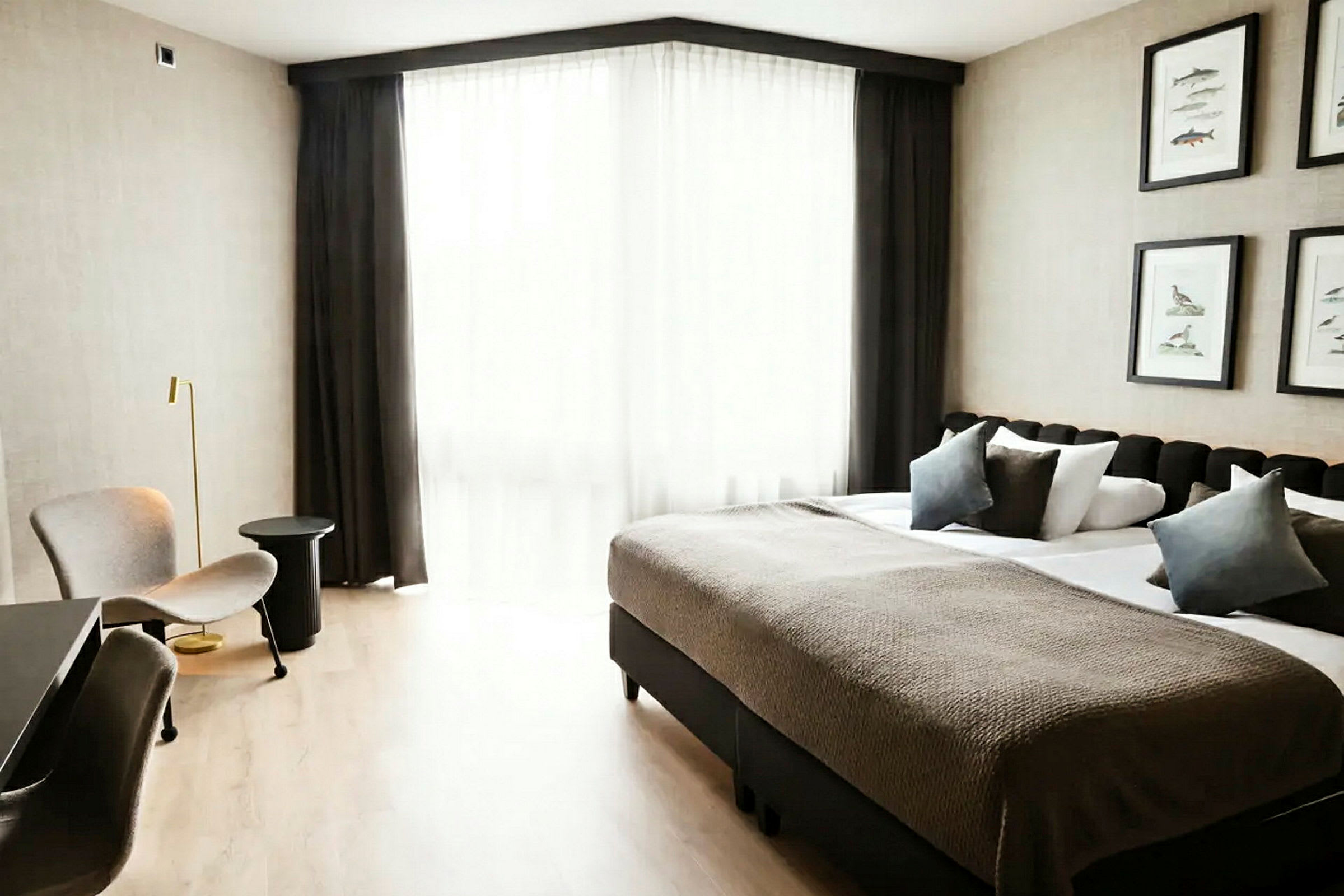Et hotelværelse med en dobbeltseng, siddepladser og et stort vindue med lyse gardiner. (AI-genereret tekst)