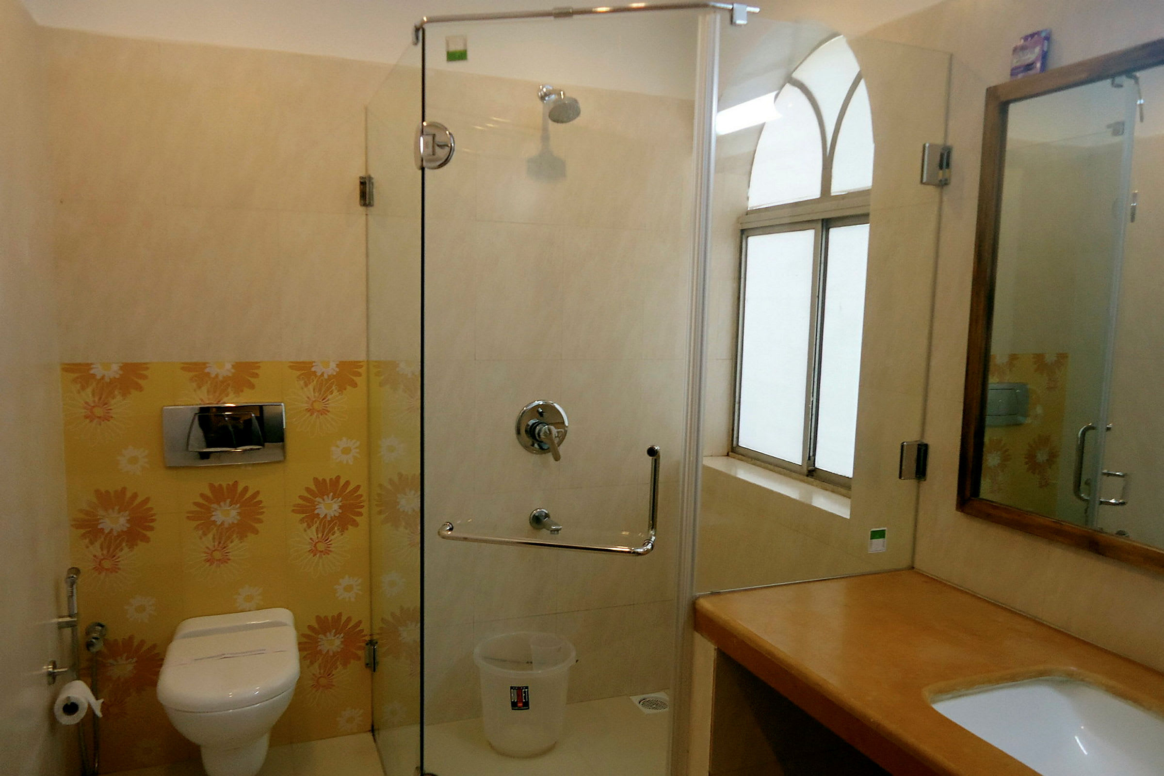 Et badeværelse med toilet, brusekabine med glasdør og en håndvask med spejl. (AI-genereret tekst)