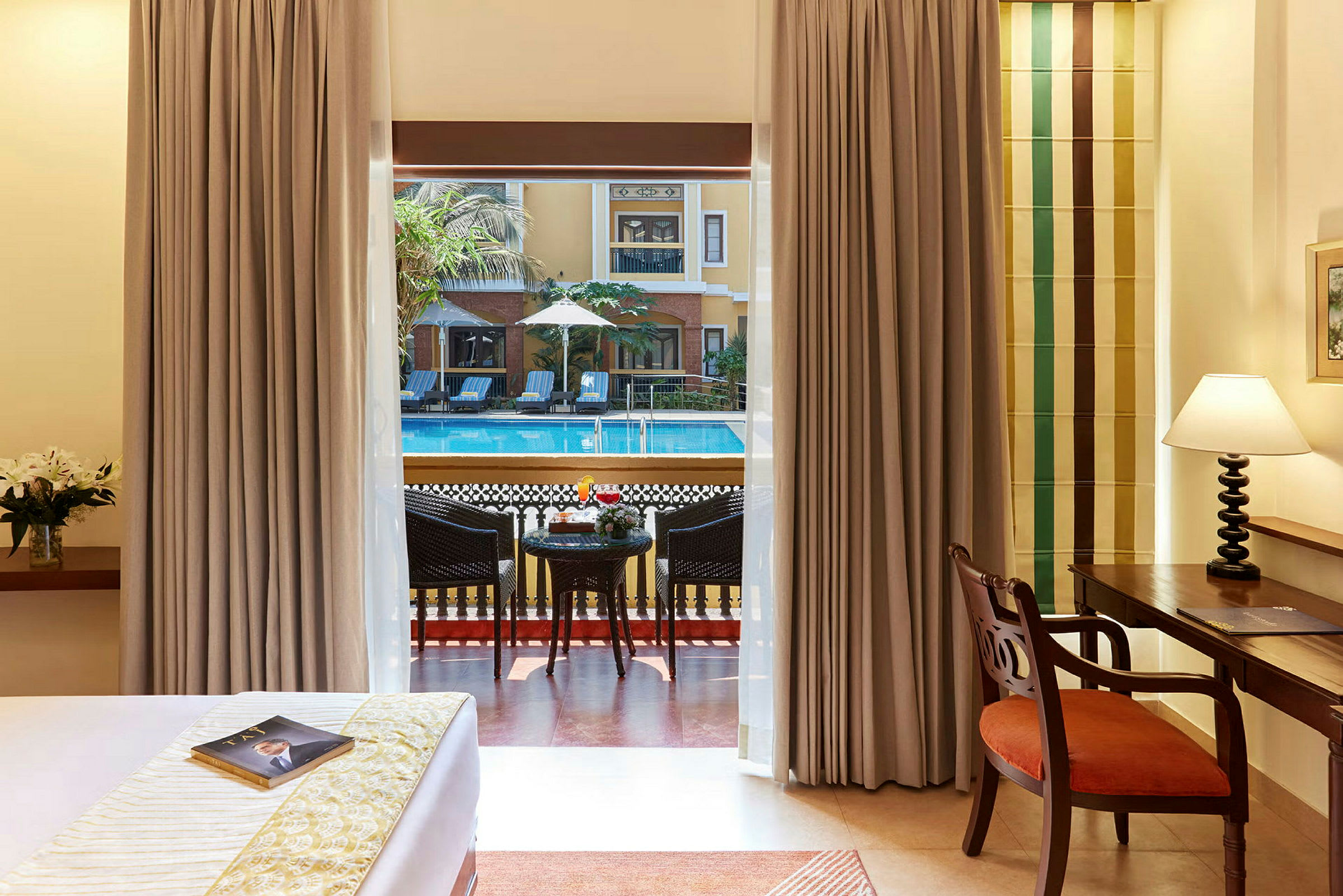 Udsigt fra hotelværelset mod terrasse og poolområde. (AI-genereret tekst)