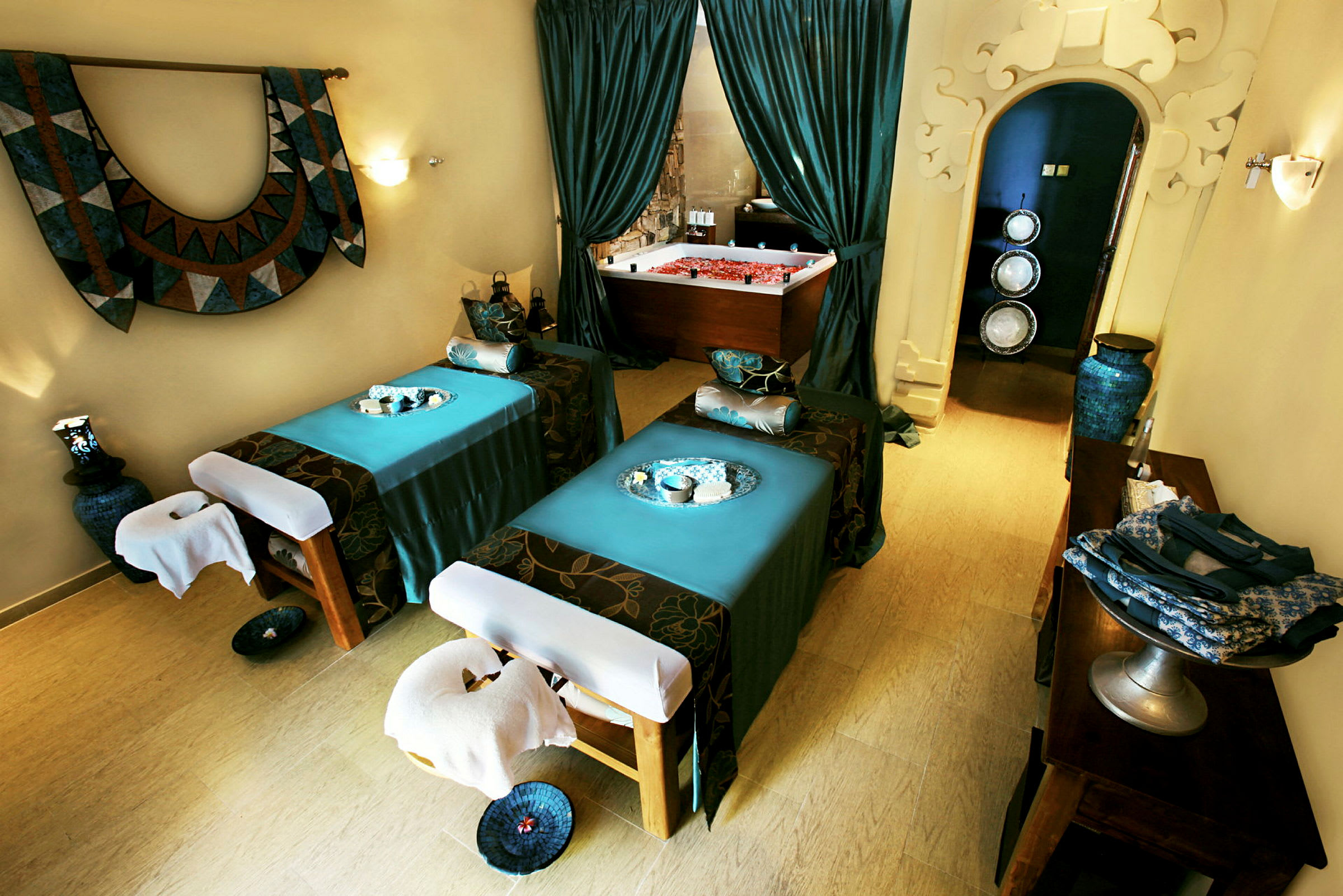 Et hyggeligt spa-rum med to massageborde og et dekorativt badekar i baggrunden. (AI-genereret tekst)