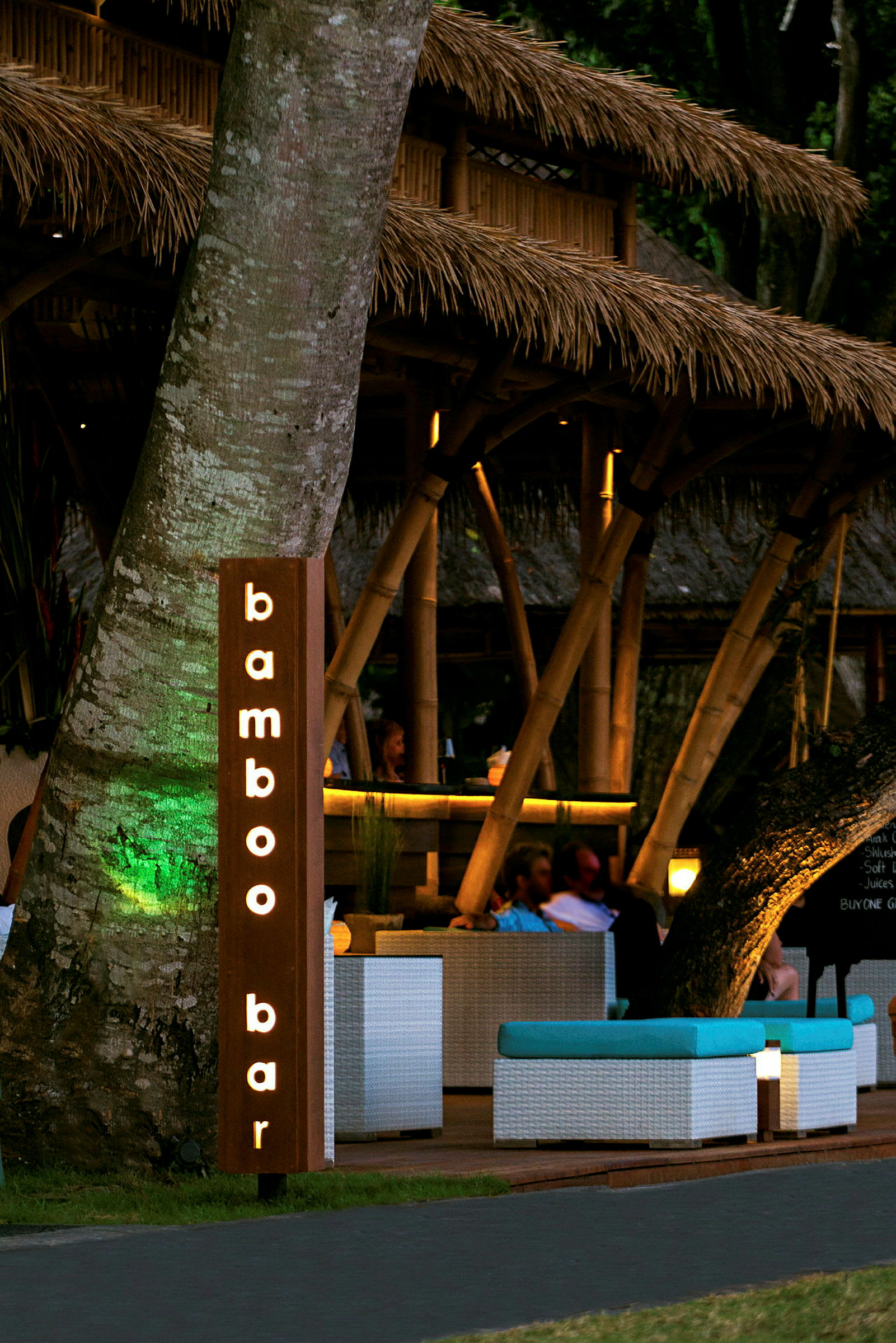 En bar med et skilt, der lyder "bamboo bar" og en indretning med bambusstruktur og siddegrupper. (AI-genereret tekst)