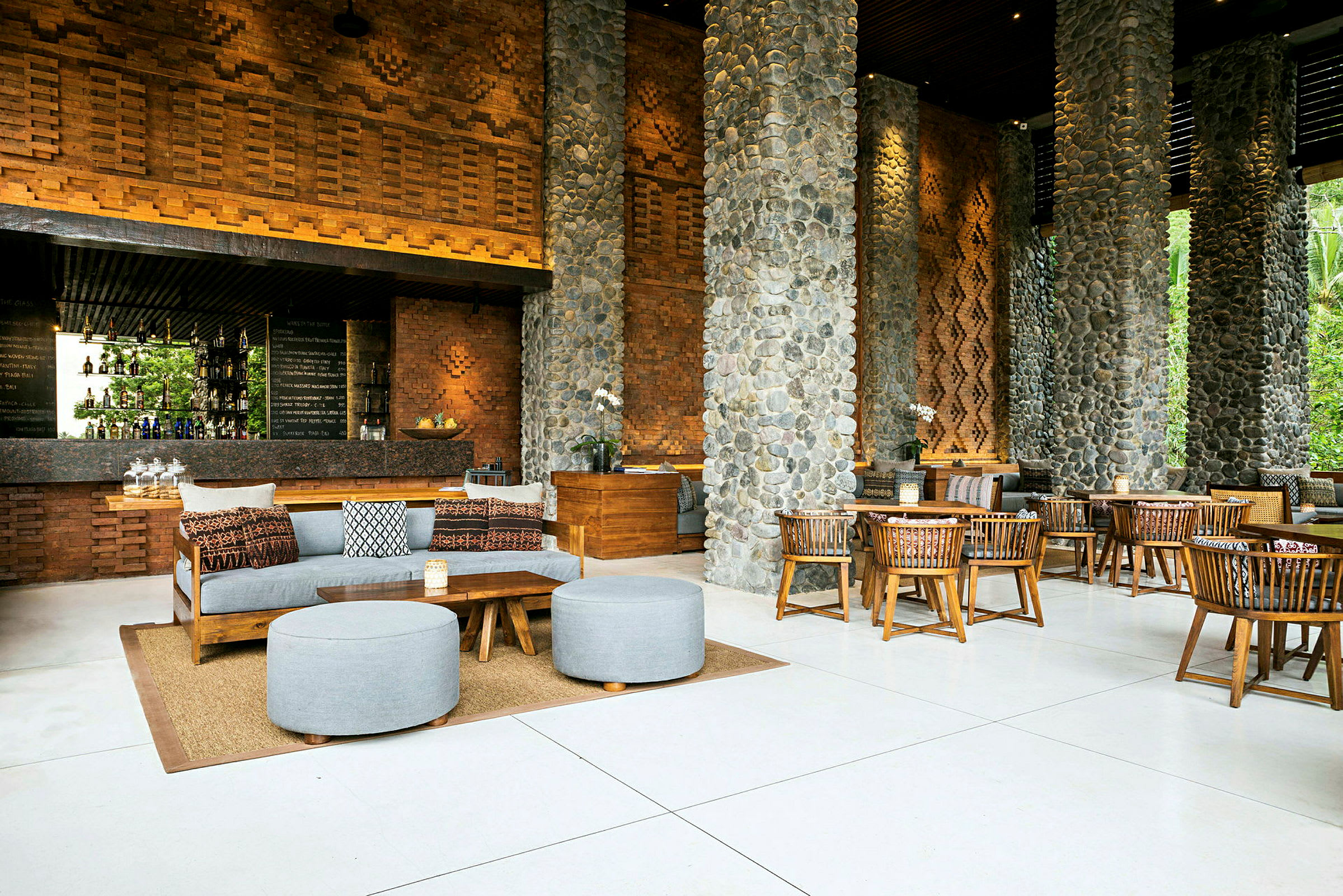Et moderne caféområde med rustikt interiør af træ og sten, kompletteret med borde, stole og sofaer. (AI-genereret tekst)