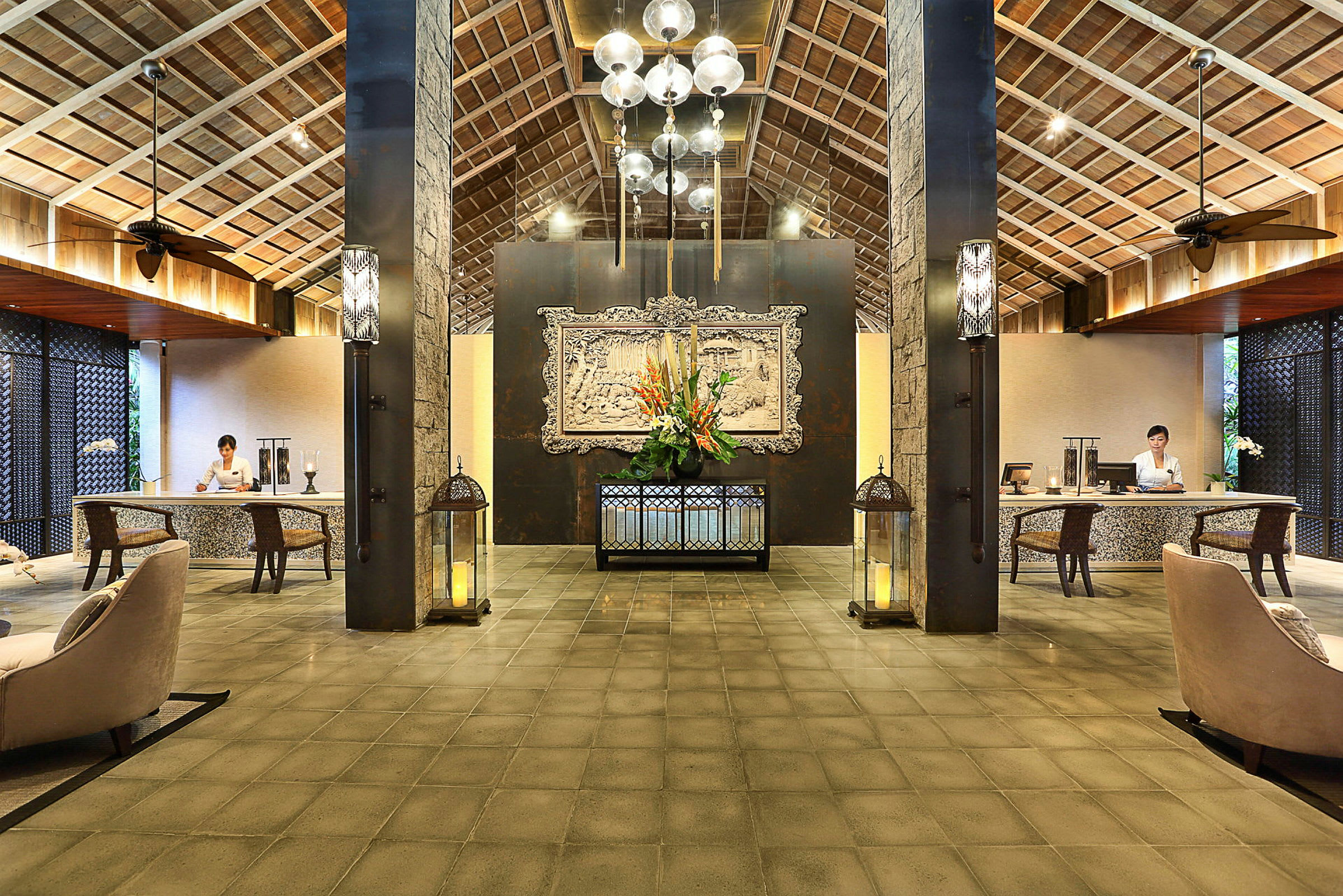 En hotellobby med højt loft af træ og dekorativ belysning samt en reception med to skriveborde. (AI-genereret tekst)