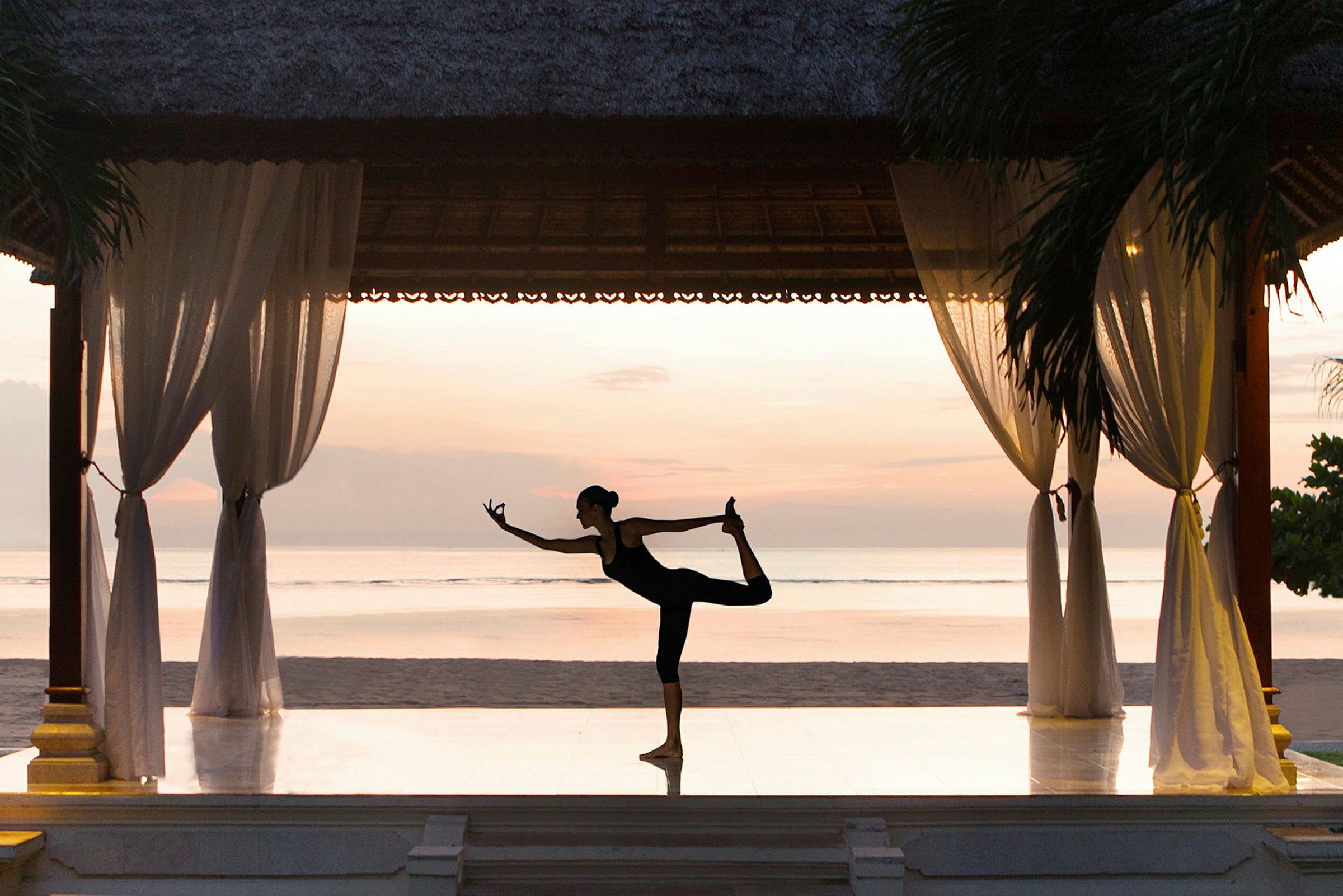 En person laver yoga på en pavillon ved stranden med en beroligende horisont i baggrunden. (AI-genereret tekst)