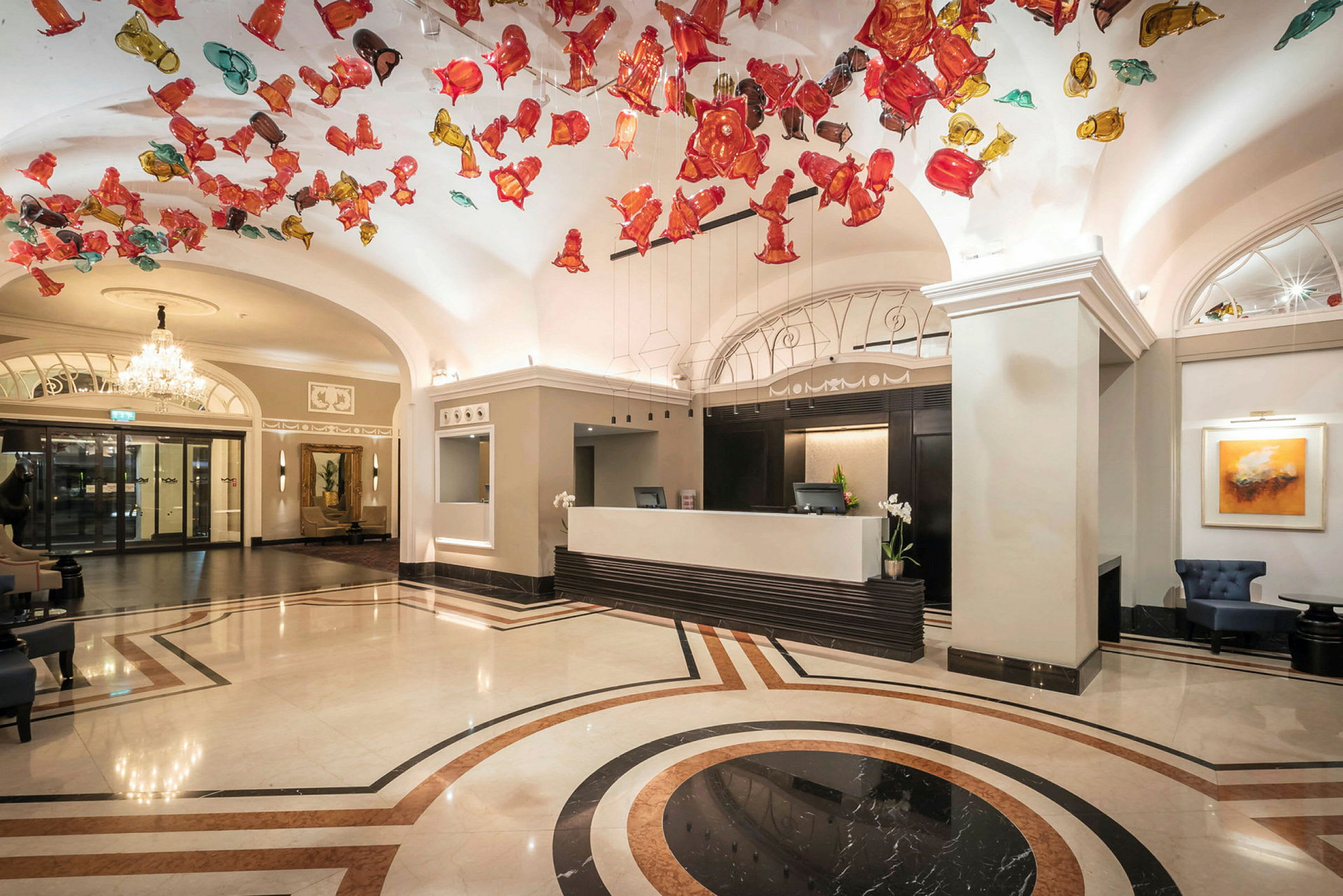 Hotellobby med reception og farverige dekorationer i loftet. (AI-genereret tekst)