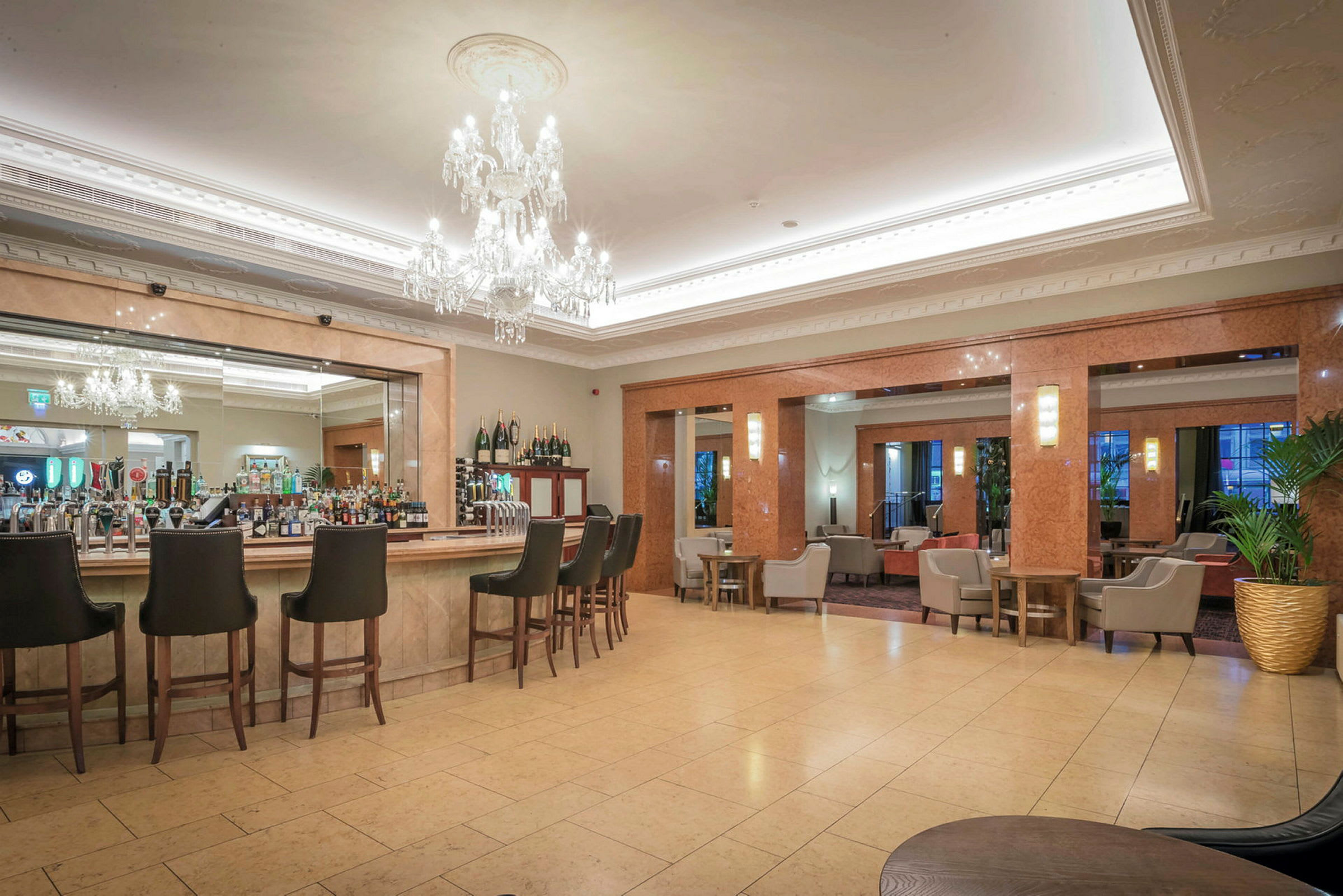 Moderne hotelbarområde med høje stole og lysekroner. (AI-genereret tekst)