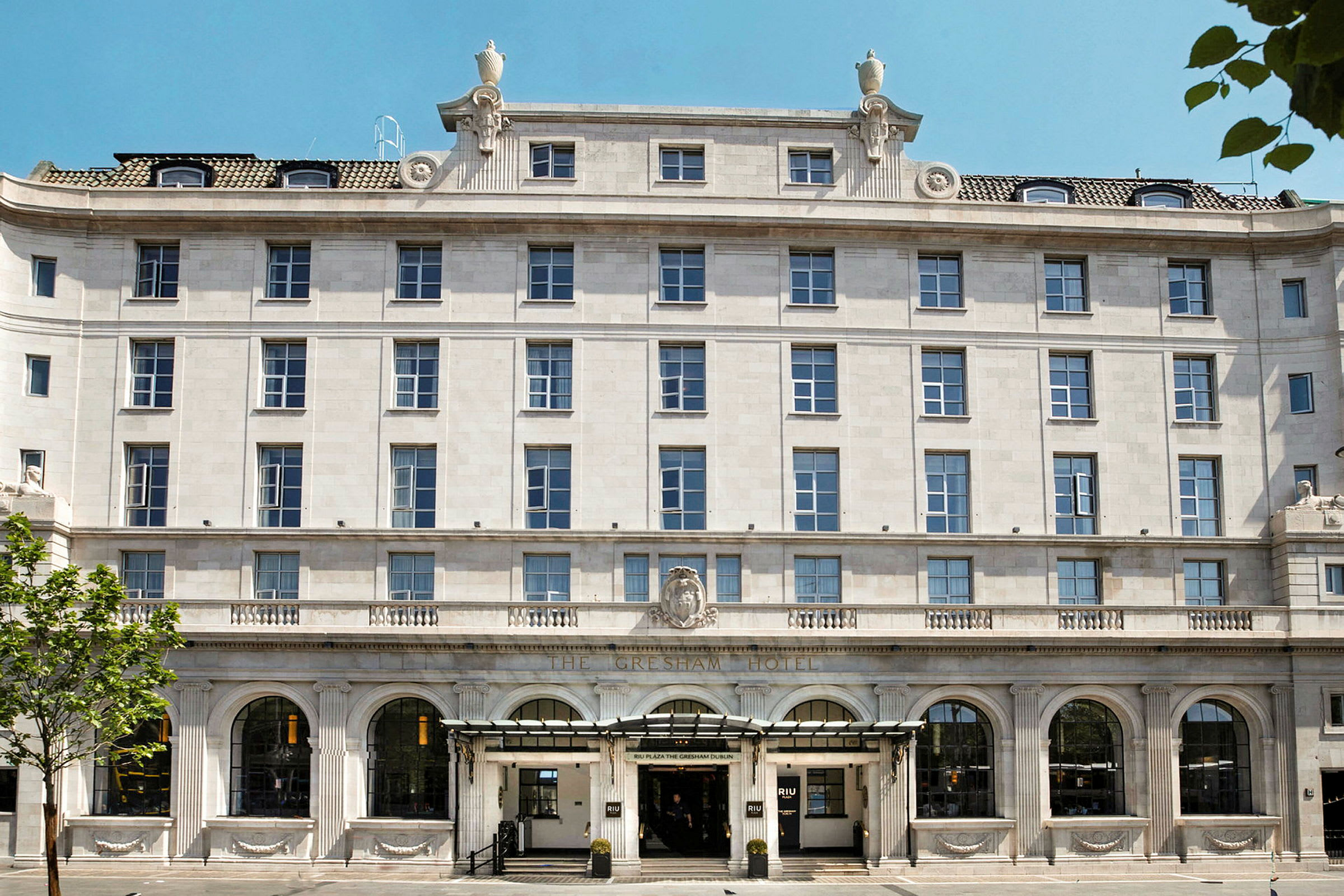 Udvendigt af et hotel med flere etager og klassisk facade med buer og søjler. (AI-genereret tekst)