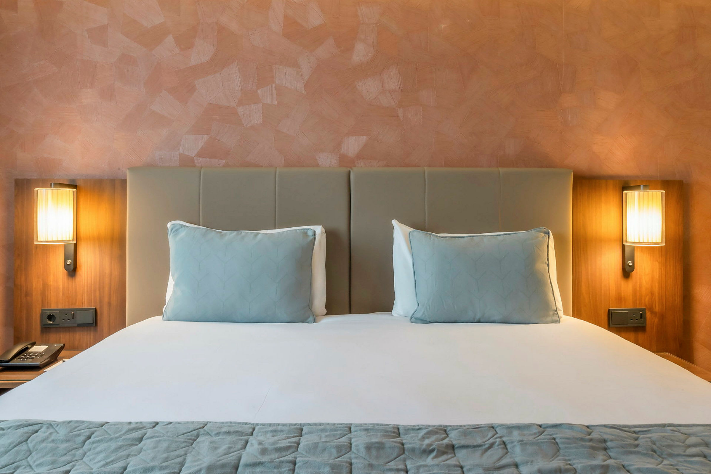 Hotelseng med to puder og to natbordslamper. (AI-genereret tekst)