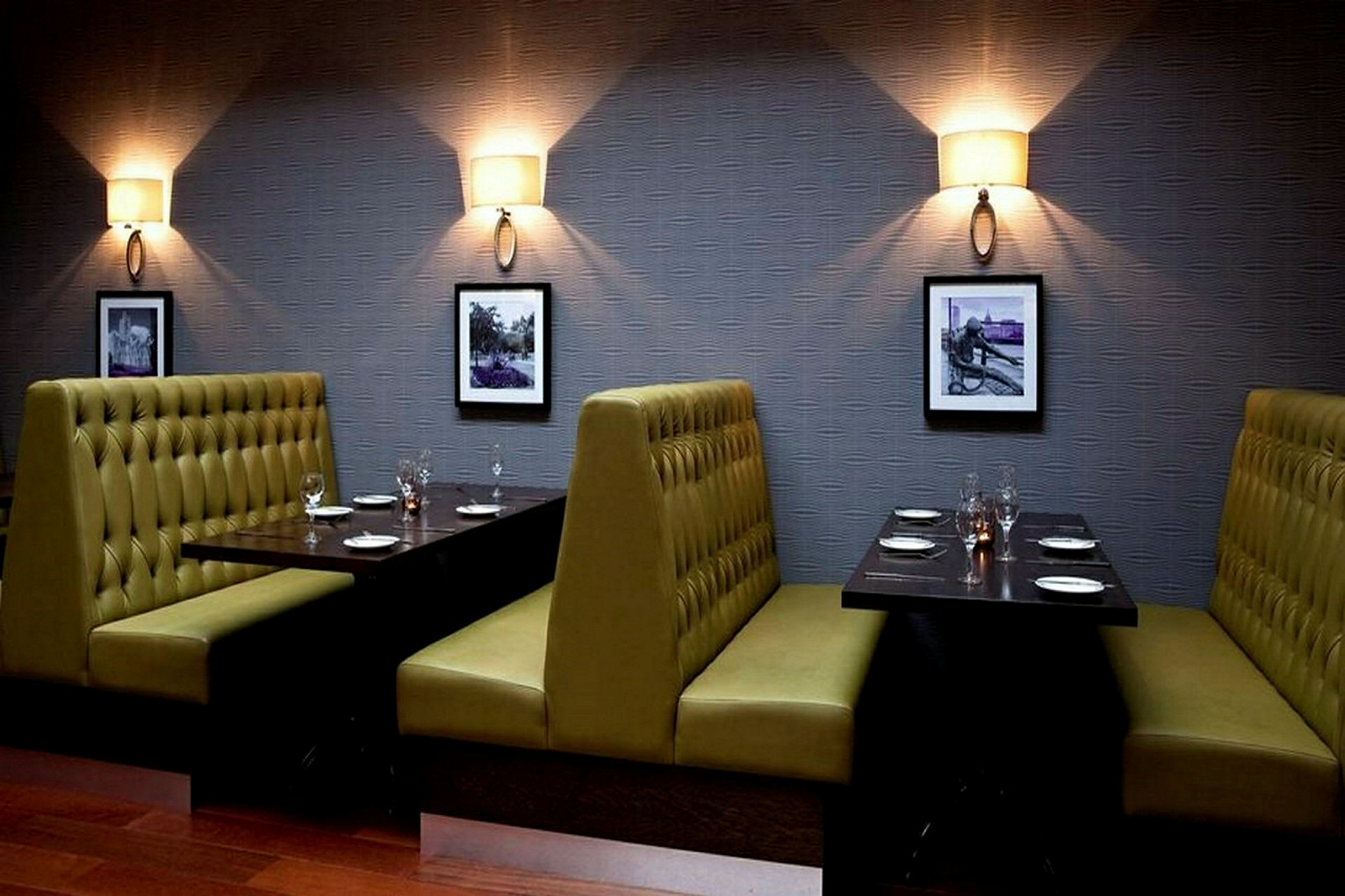 Billede af en restaurant med siddepladser i båse. Væggene er dekoreret med små billeder og væglamper. (AI-genereret tekst)