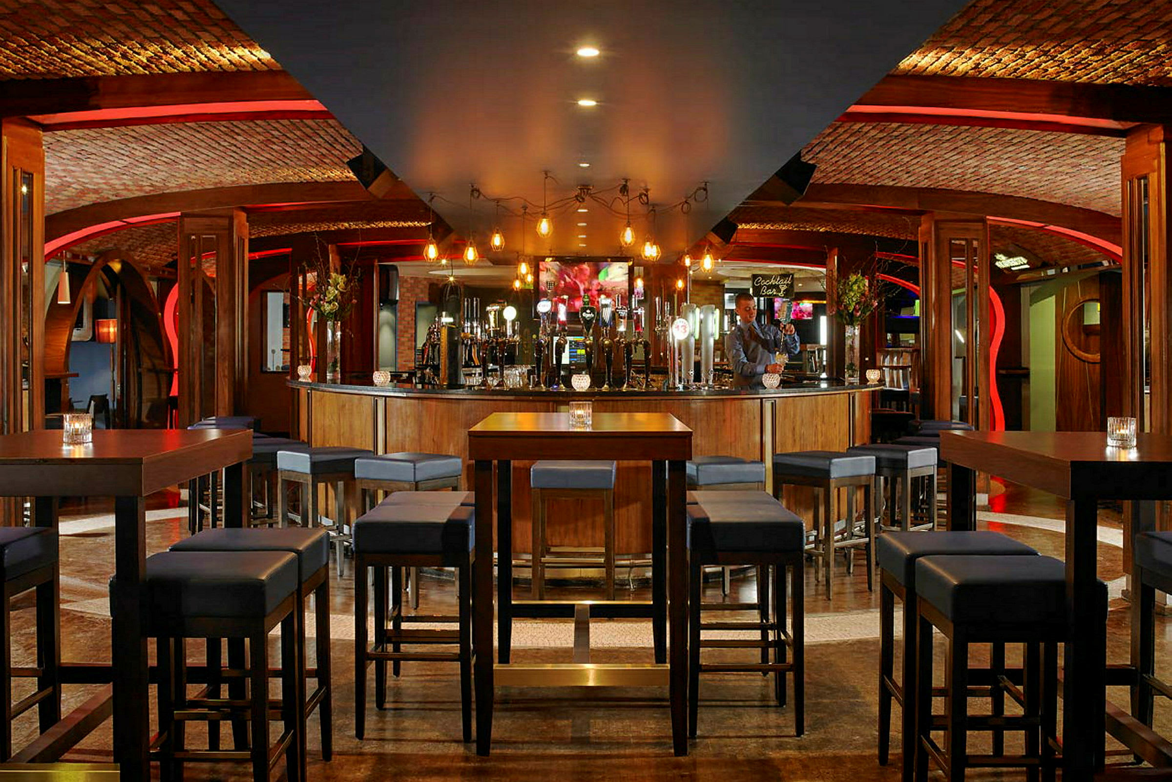 Interiør af en restaurant med høje borde og stole arrangeret i et rum med stemningsfuld belysning. (AI-genereret tekst)