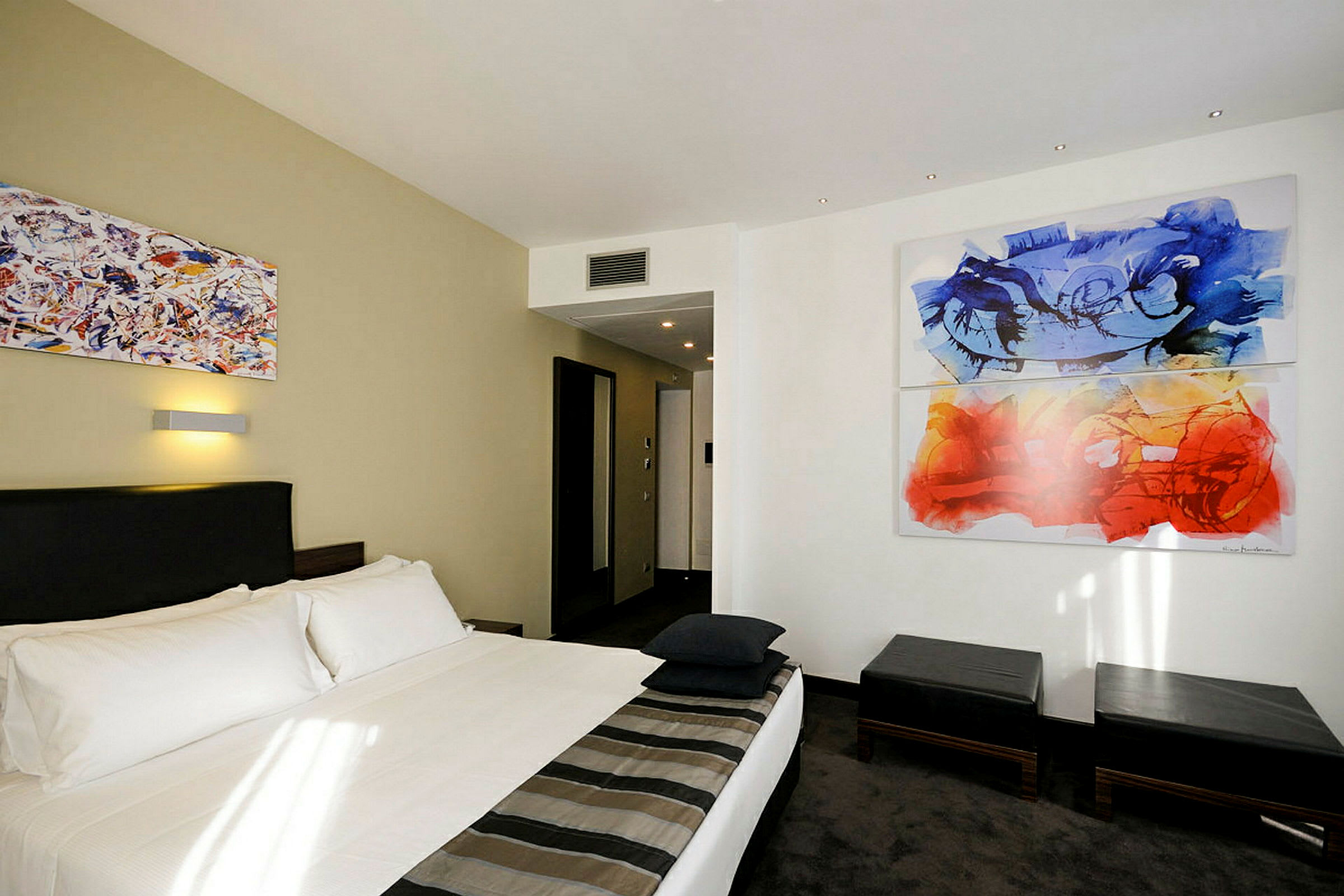 Hotelværelse med en dobbeltseng og abstrakt kunst på væggen. (AI-genereret tekst)