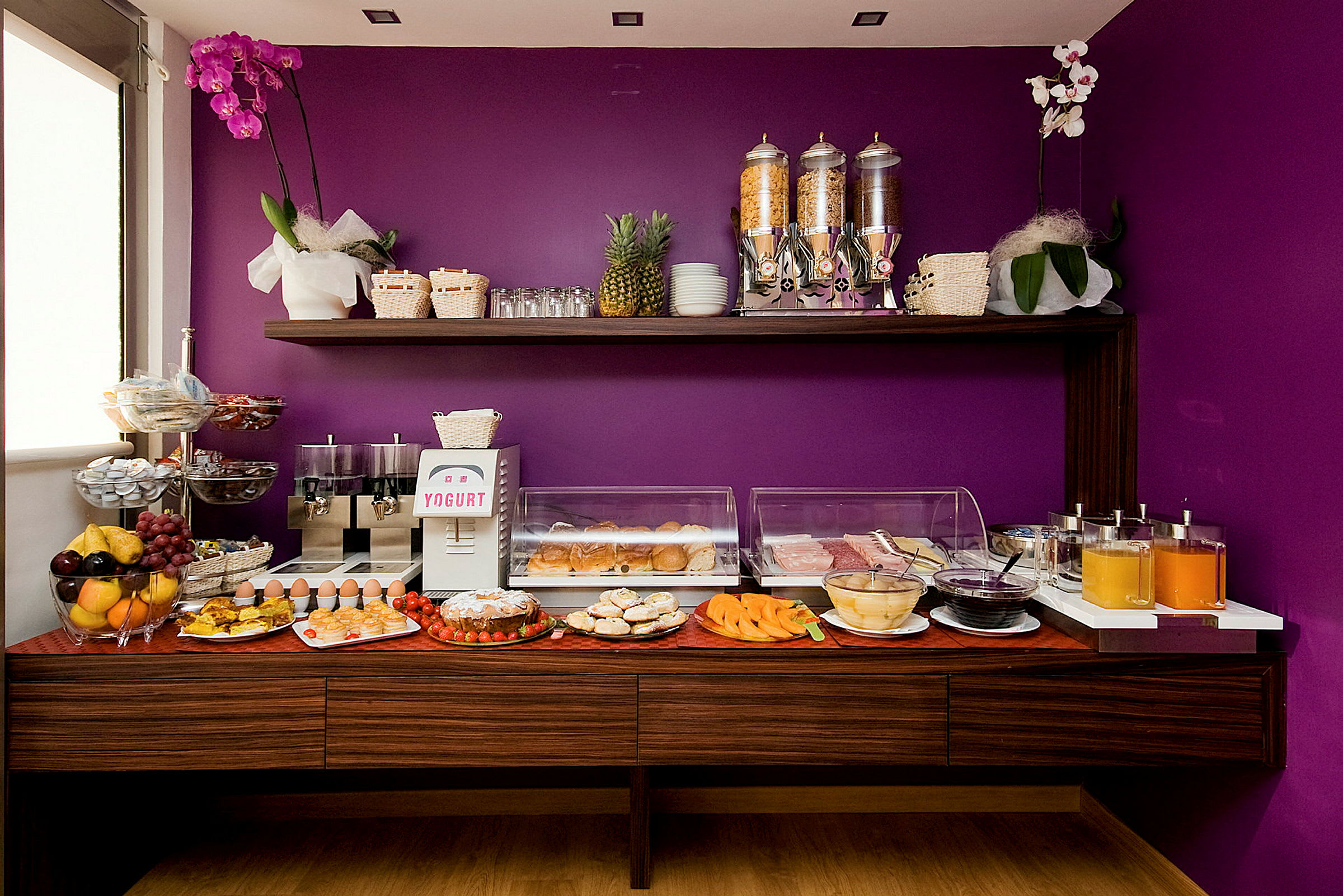 Buffet med morgenmad og drikkevarer mod en lilla baggrund. (AI-genereret tekst)
