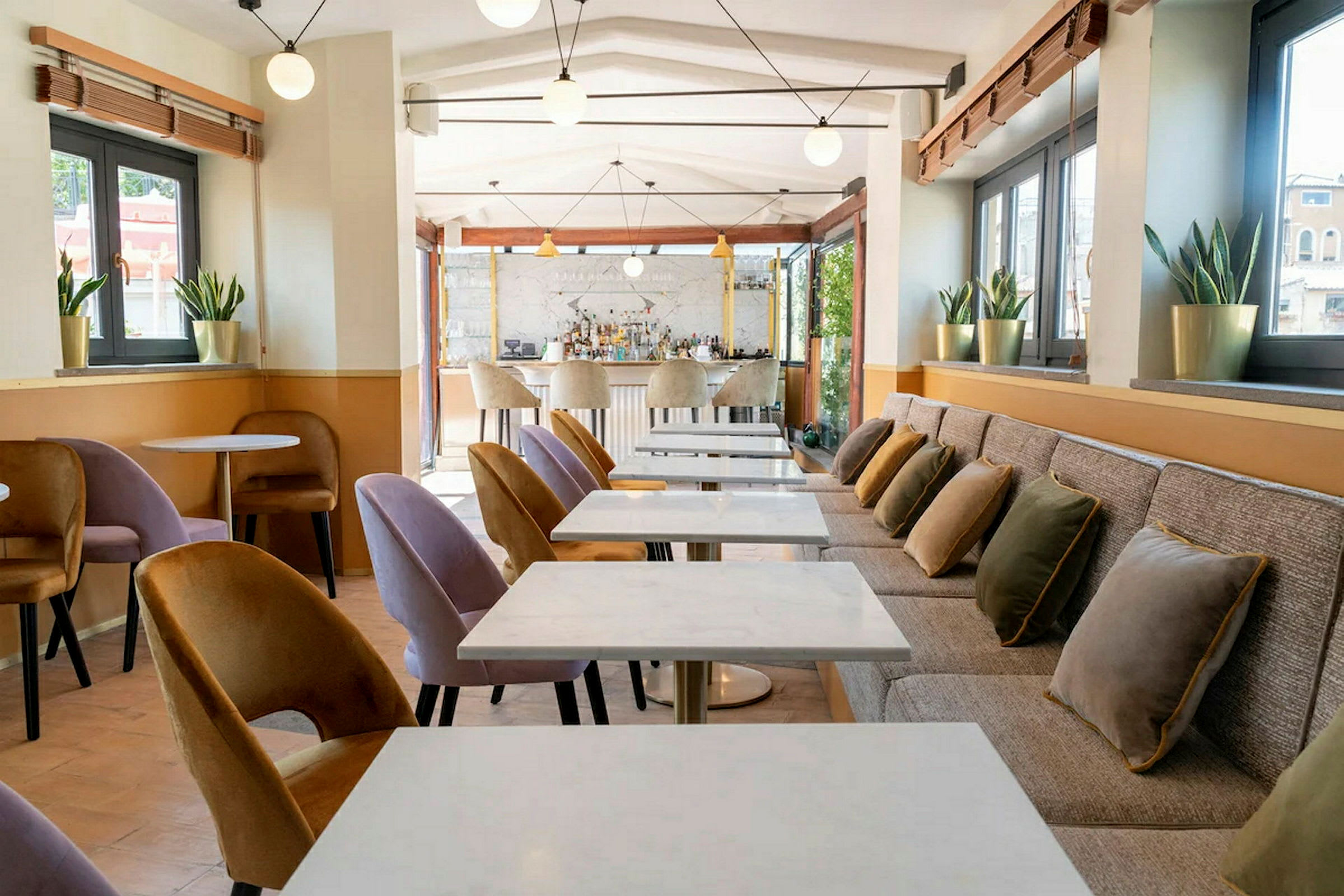 En moderne café med marmorborde, polstrede stole og puder på en lang bænk. (AI-genereret tekst)