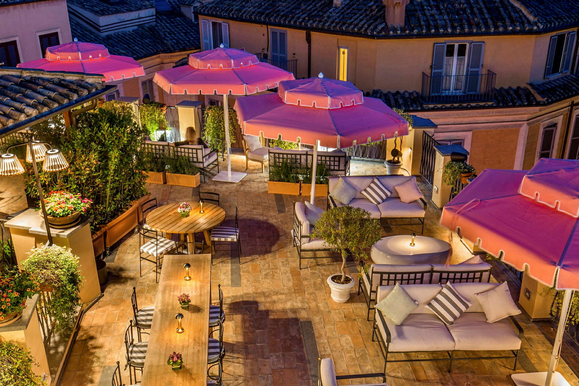 En udendørs terrasse med siddegrupper, borde og pink parasoller. (AI-genereret tekst)