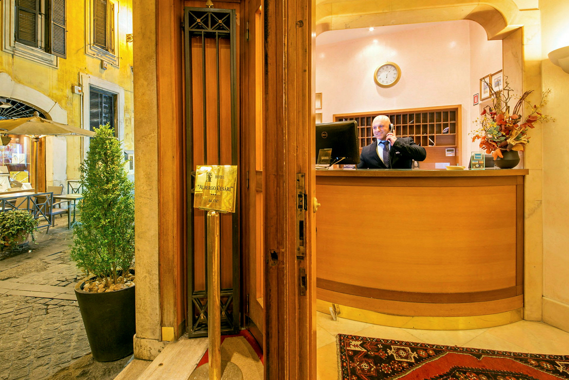 Indgangen til Hotel Albergo Cesari med receptionen og omgivende indretning. (AI-genereret tekst)