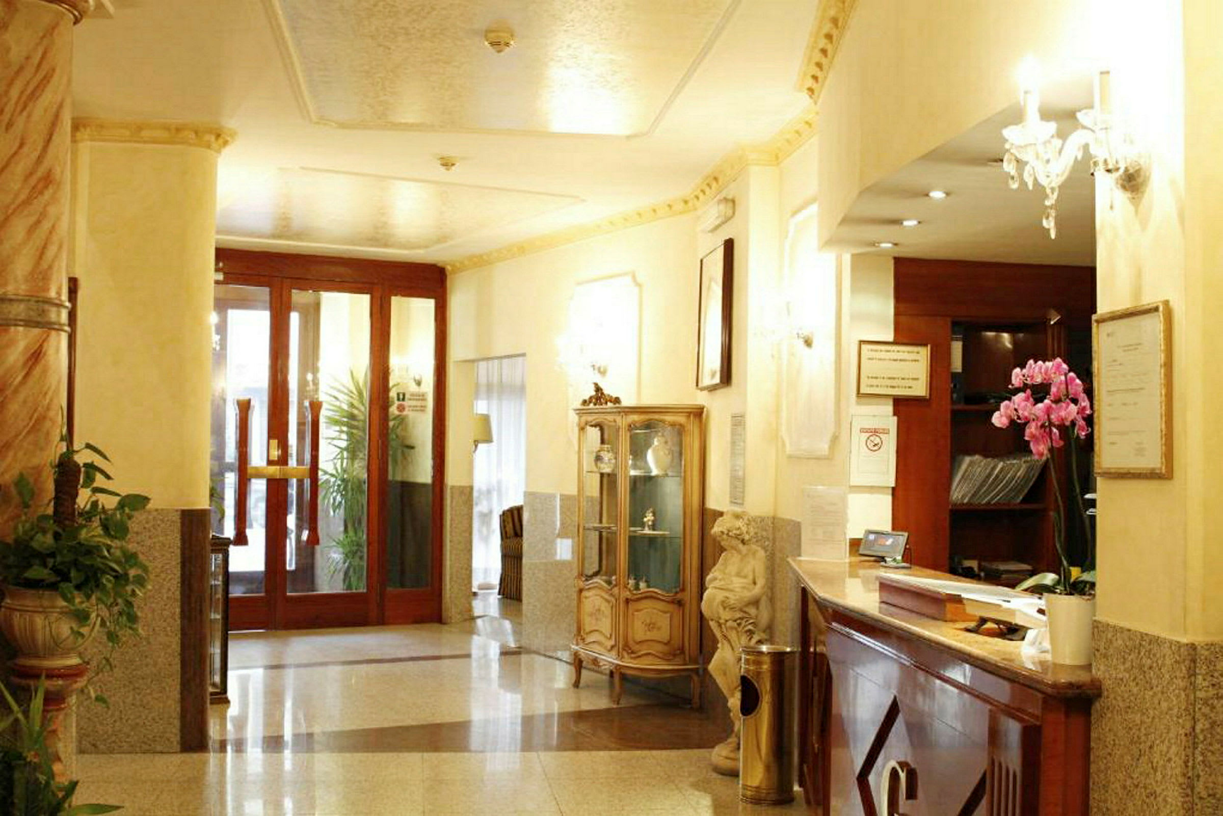Interiør af en hotellobby med reception, glasskab, planter og ornamenter. (AI-genereret tekst)