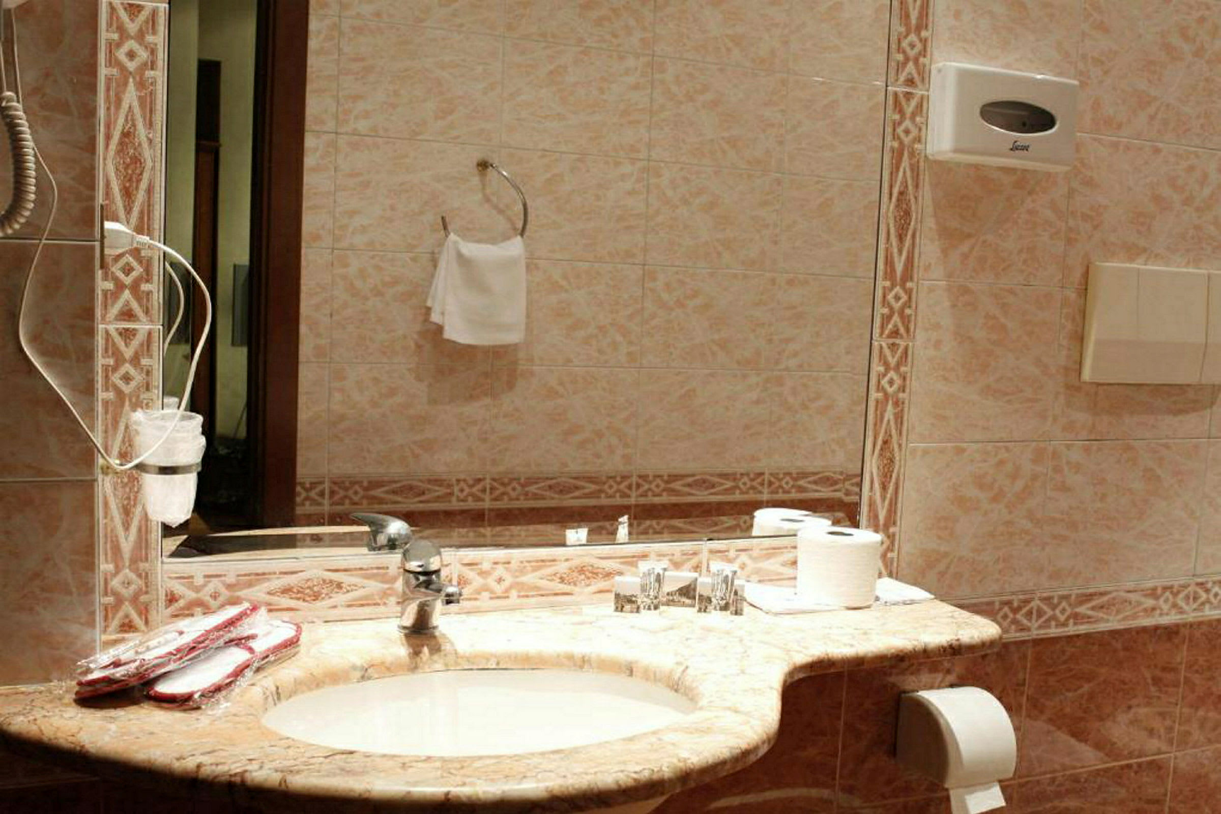 Et badeværelse med et spejl, en håndvask og toiletartikler på bordet. (AI-genereret tekst)