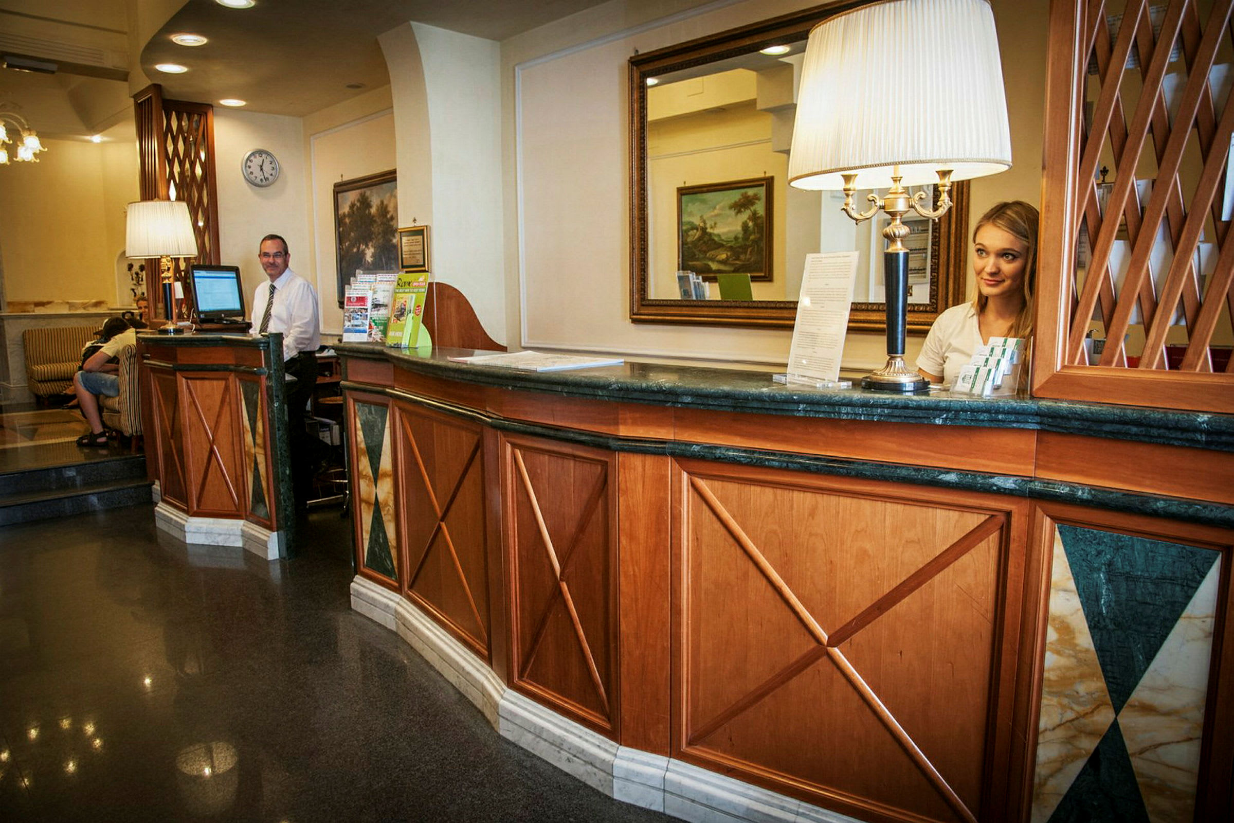 Receptionen på et hotel med træpaneler, et spejl på væggen og informationsmateriale på skranken. (AI-genereret tekst)