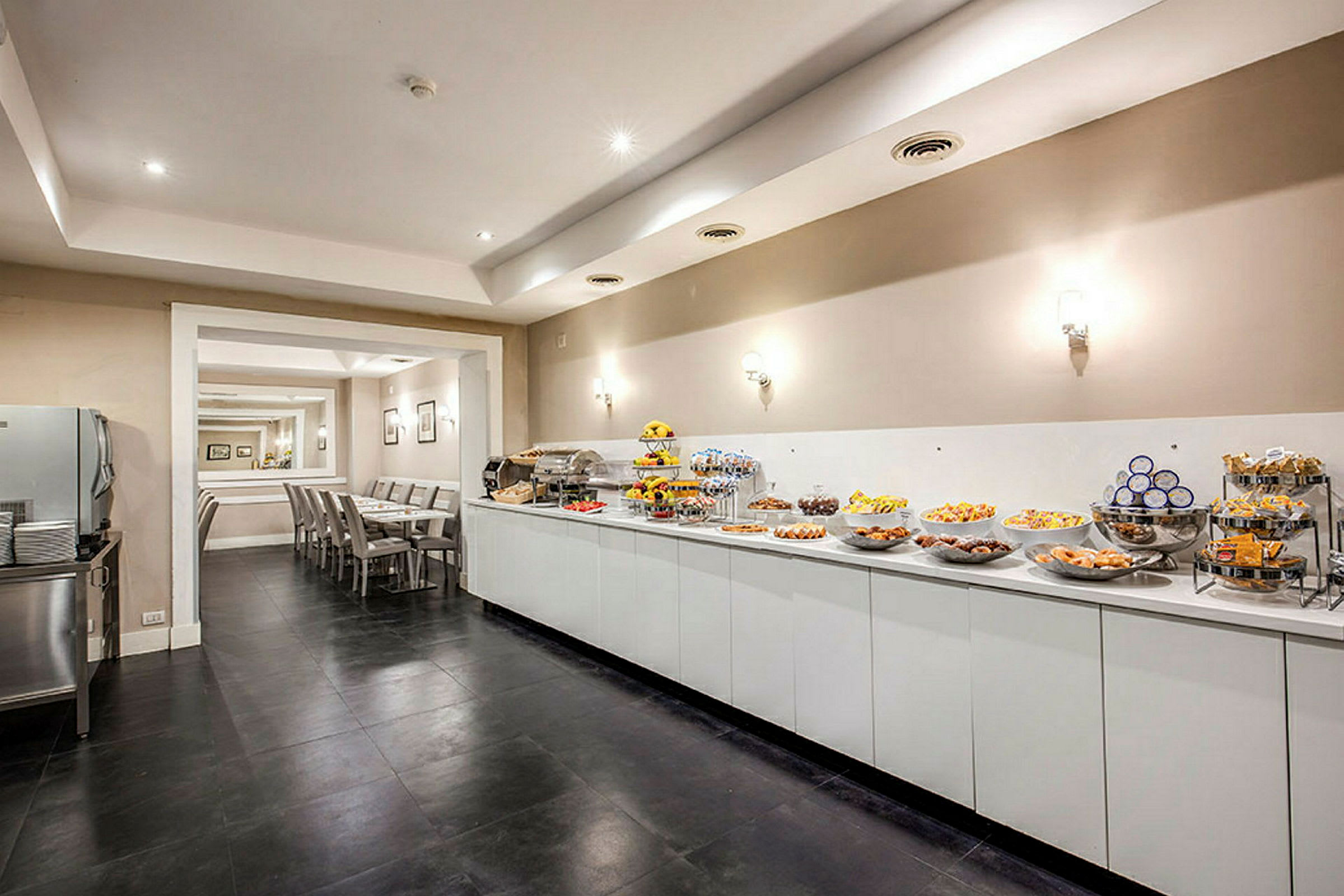 En buffet med forskellige retter og snacks foran et siddeområde med borde og stole. (AI-genereret tekst)