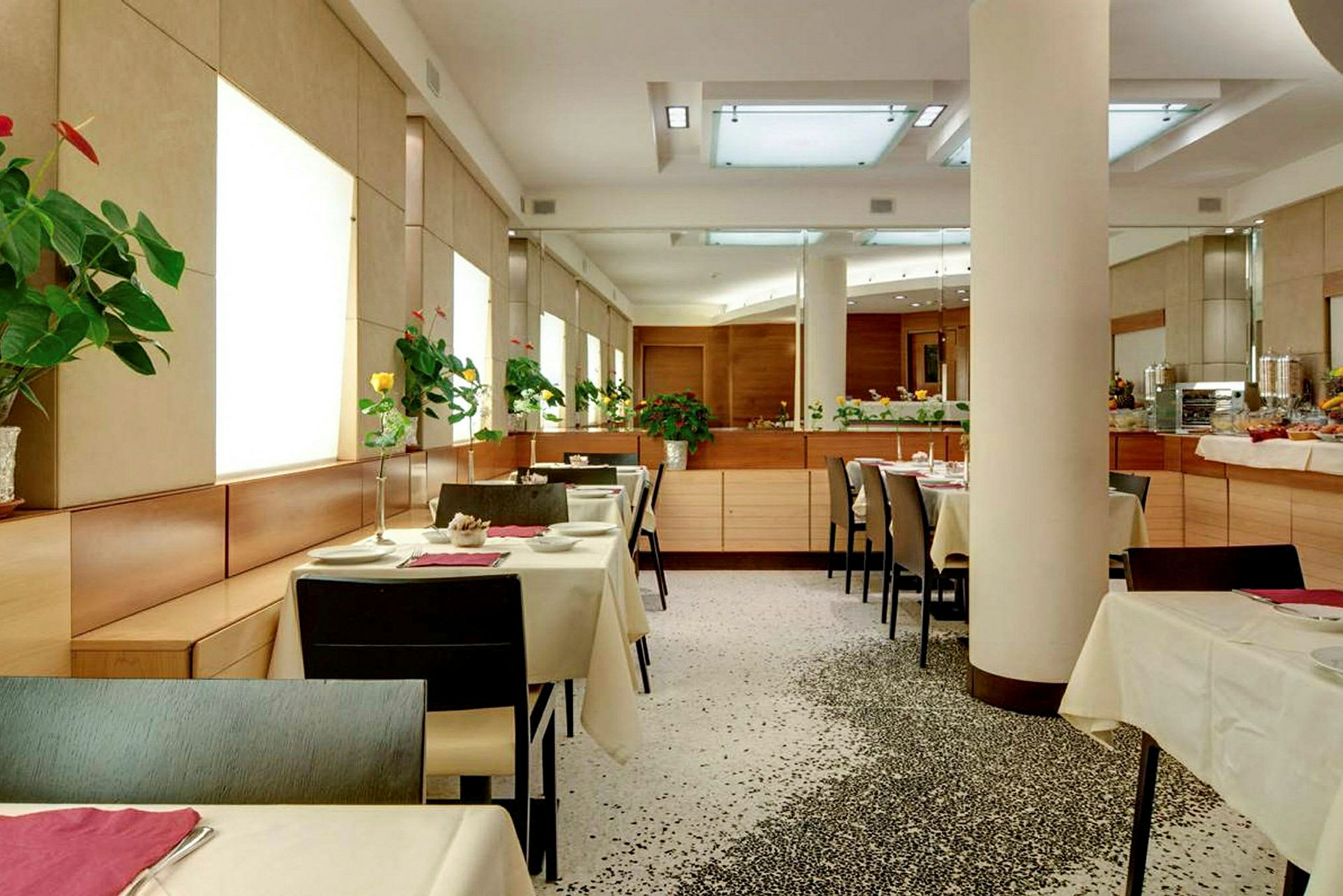 En moderne restaurant med opsatte borde og blomster på hvert bord. (AI-genereret tekst)