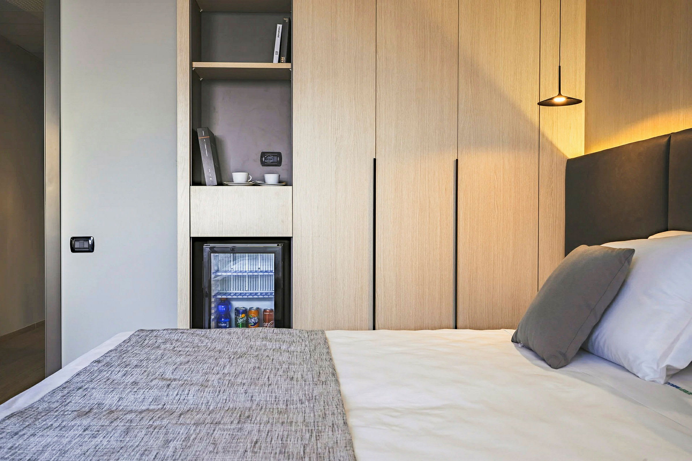 Hotelværelse med seng, minibar og garderobeskabe. (AI-genereret tekst)