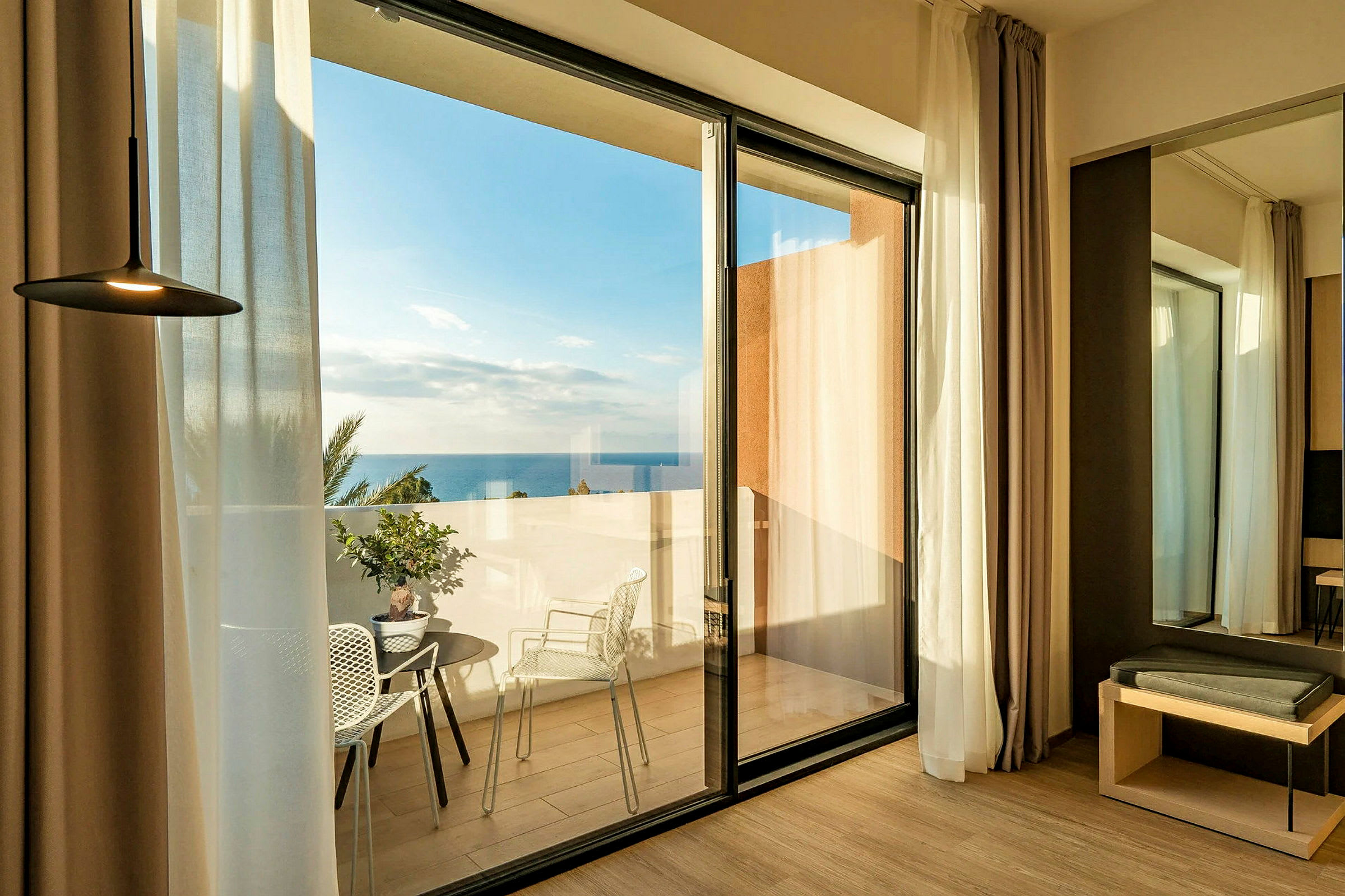 Hotelværelse med glasdøre, der åbner ud til en terrasse med havudsigt. (AI-genereret tekst)