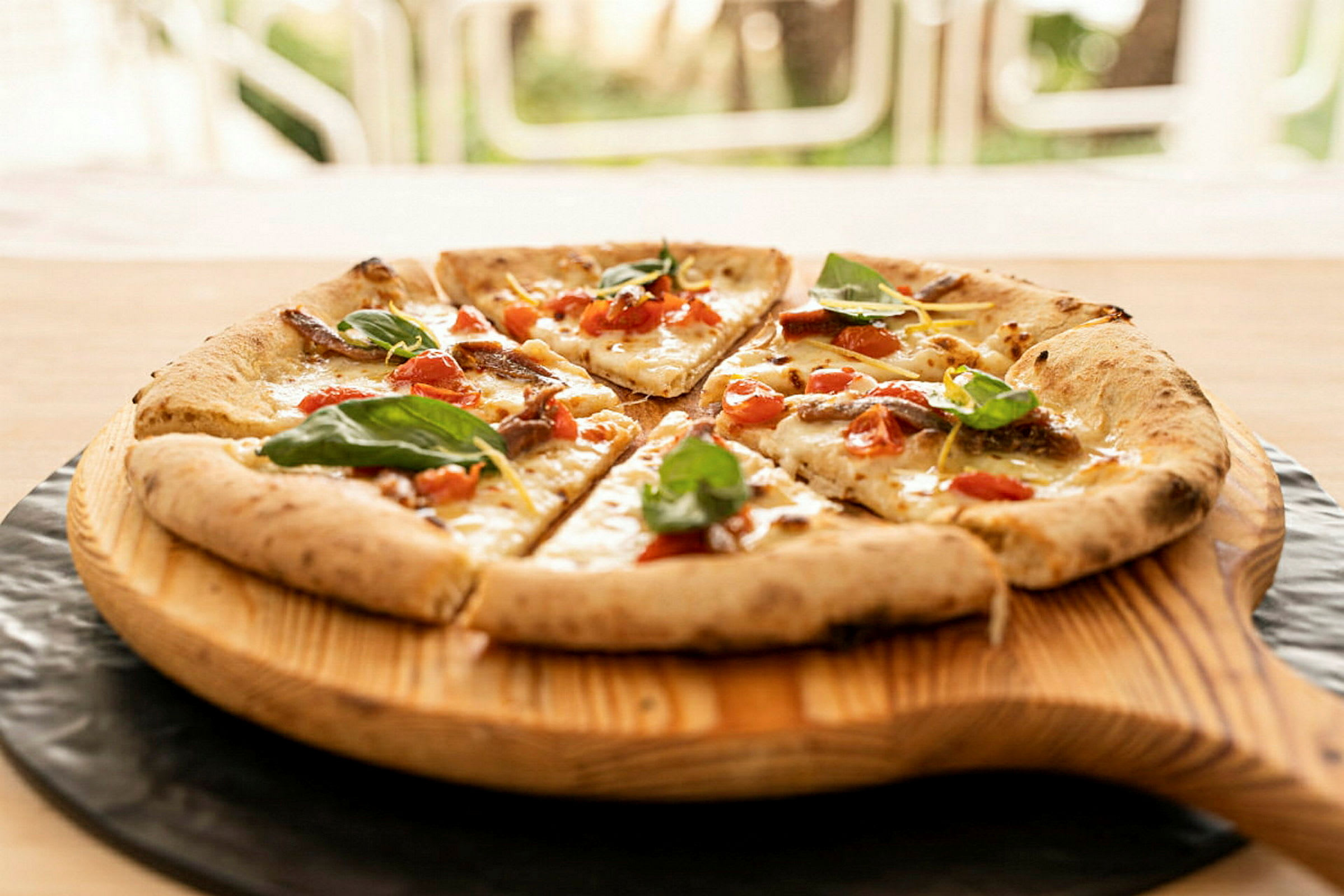 En pizza med tomat, ost og bladkrydder serveret på en træbakke. (AI-genereret tekst)