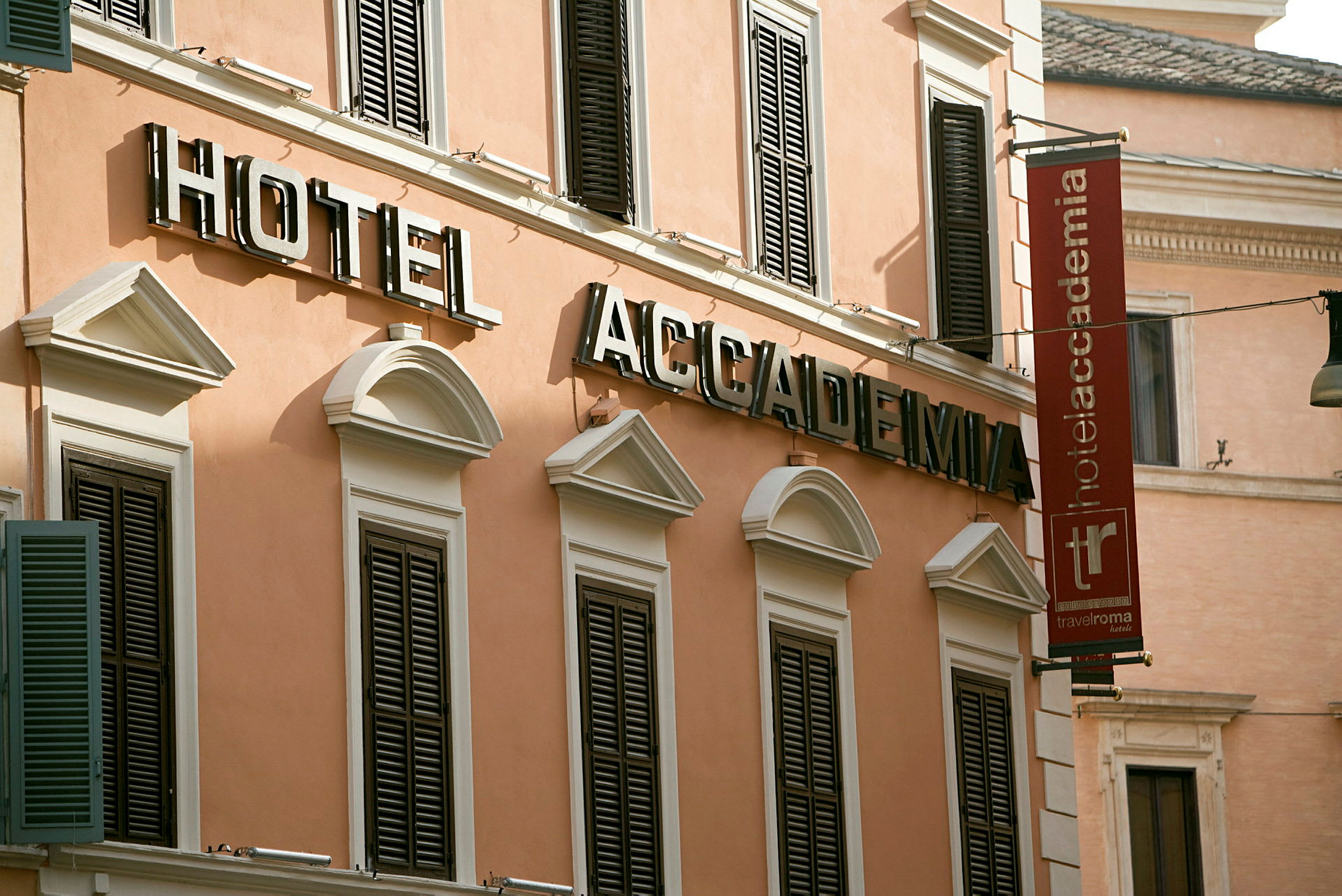 Facade af hotelbygning med skilte, der siger "Hotel Accademia" i store bogstaver. (AI-genereret tekst)