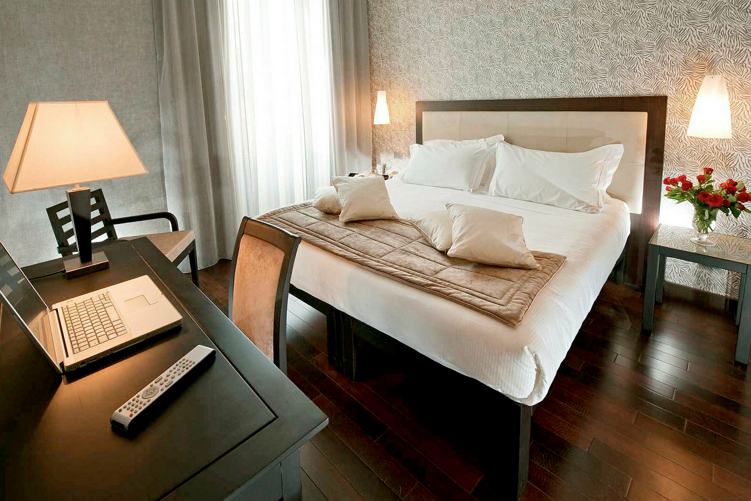 Billede af et moderne hotelværelse med en dobbeltseng, skrivebord og en bærbar computer. (AI-genereret tekst)