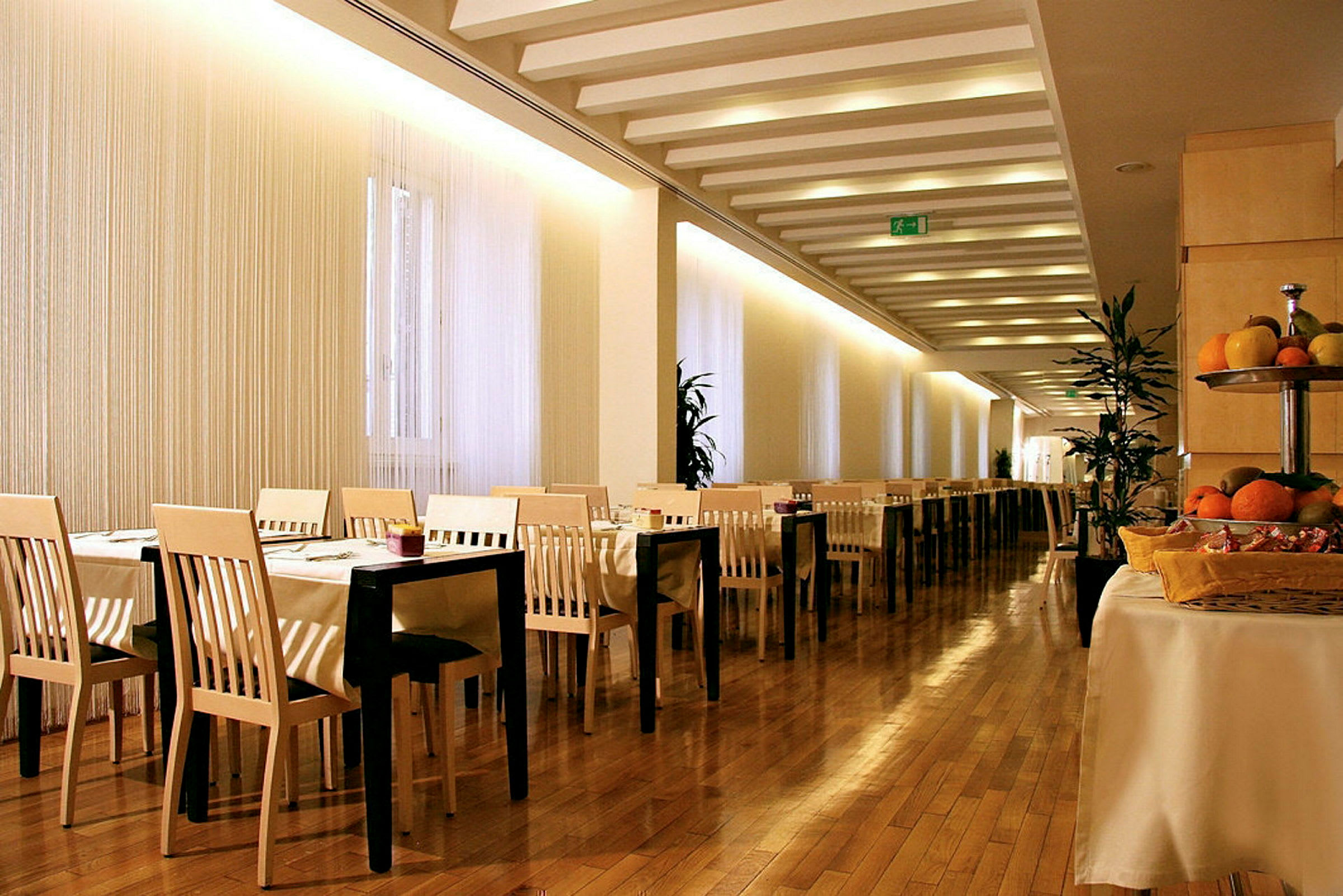 Billede af en restaurant med borde og stole, trægulv og frugt på et bord. (AI-genereret tekst)