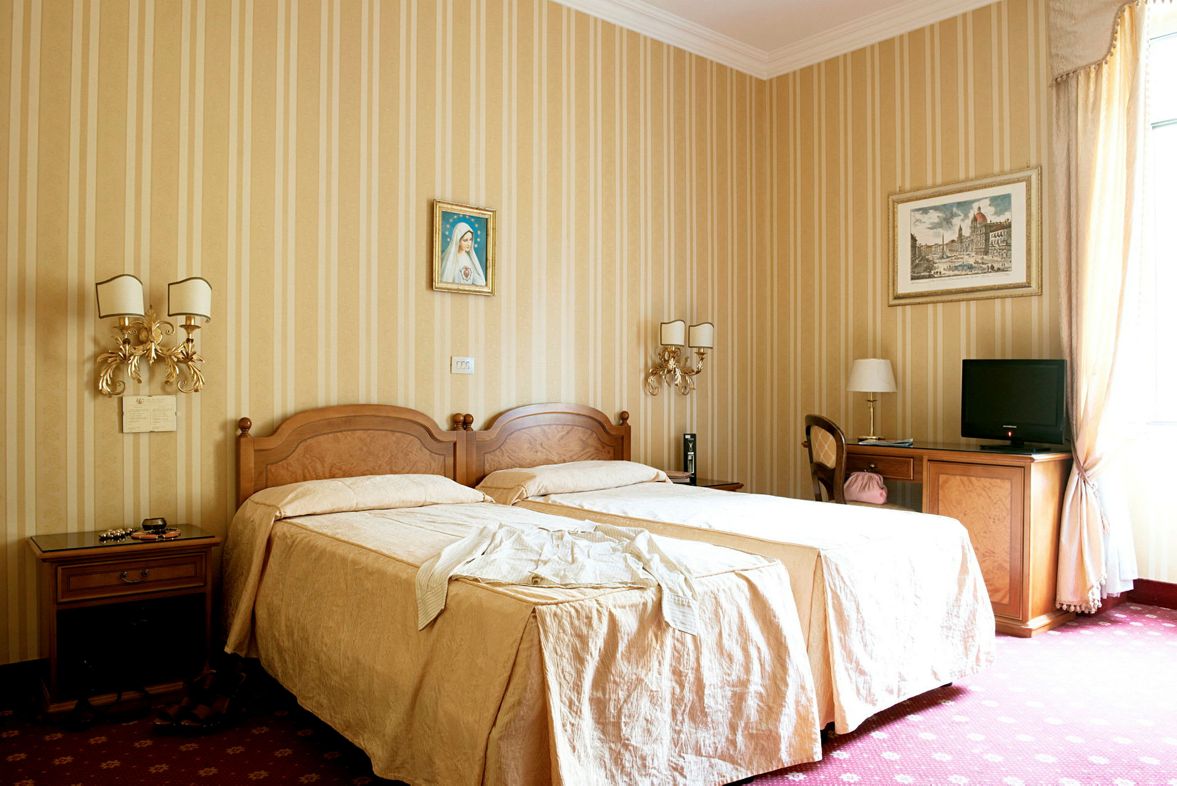Et hotelværelse med to enkeltsenge dækket med beige sengetøj, dekorerede vægge med malerier og møbler inklusive borde, stole og et fjernsyn. (AI-genereret tekst)