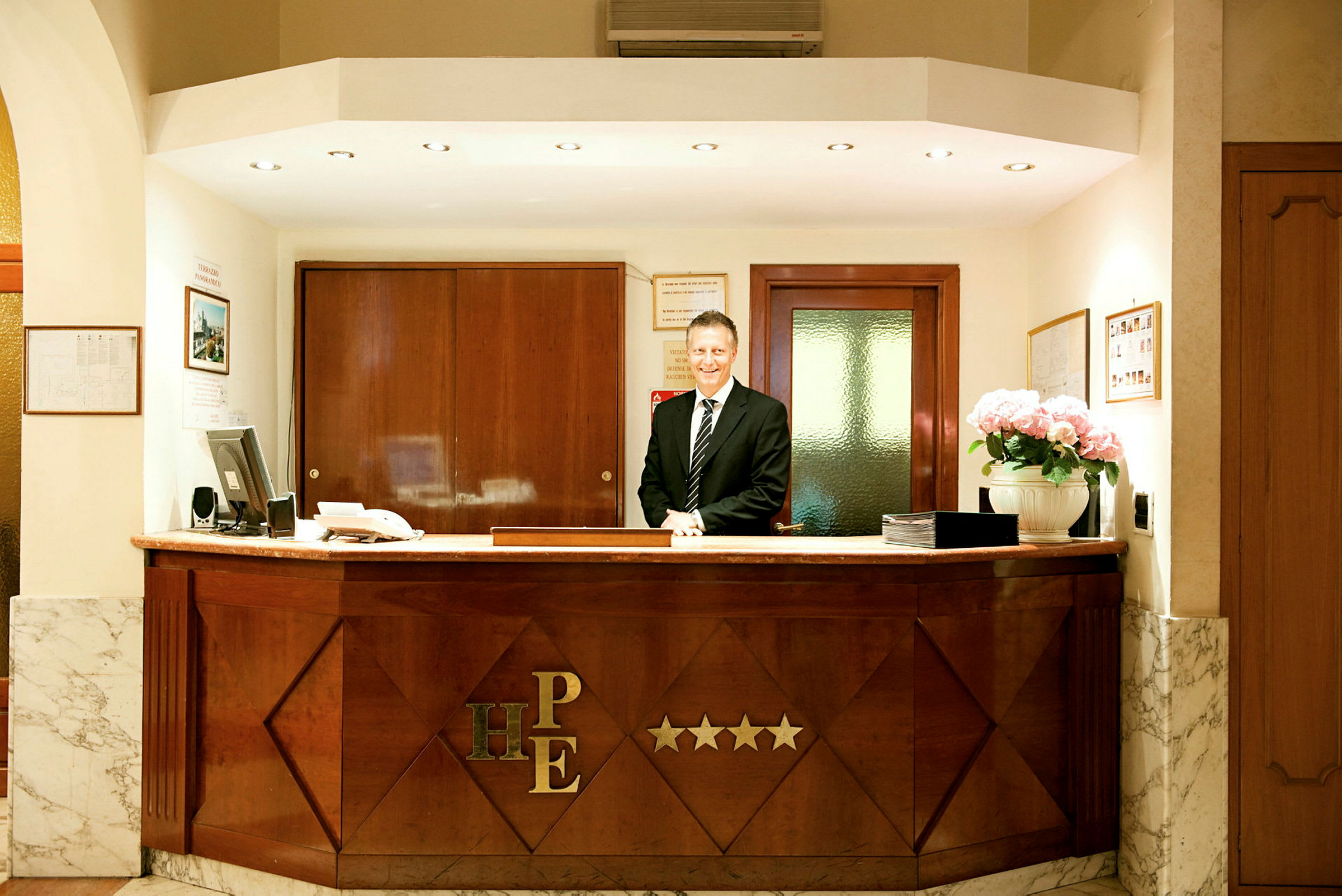 Receptionen på et hotel med en skranke og personale i jakkesæt. (AI-genereret tekst)