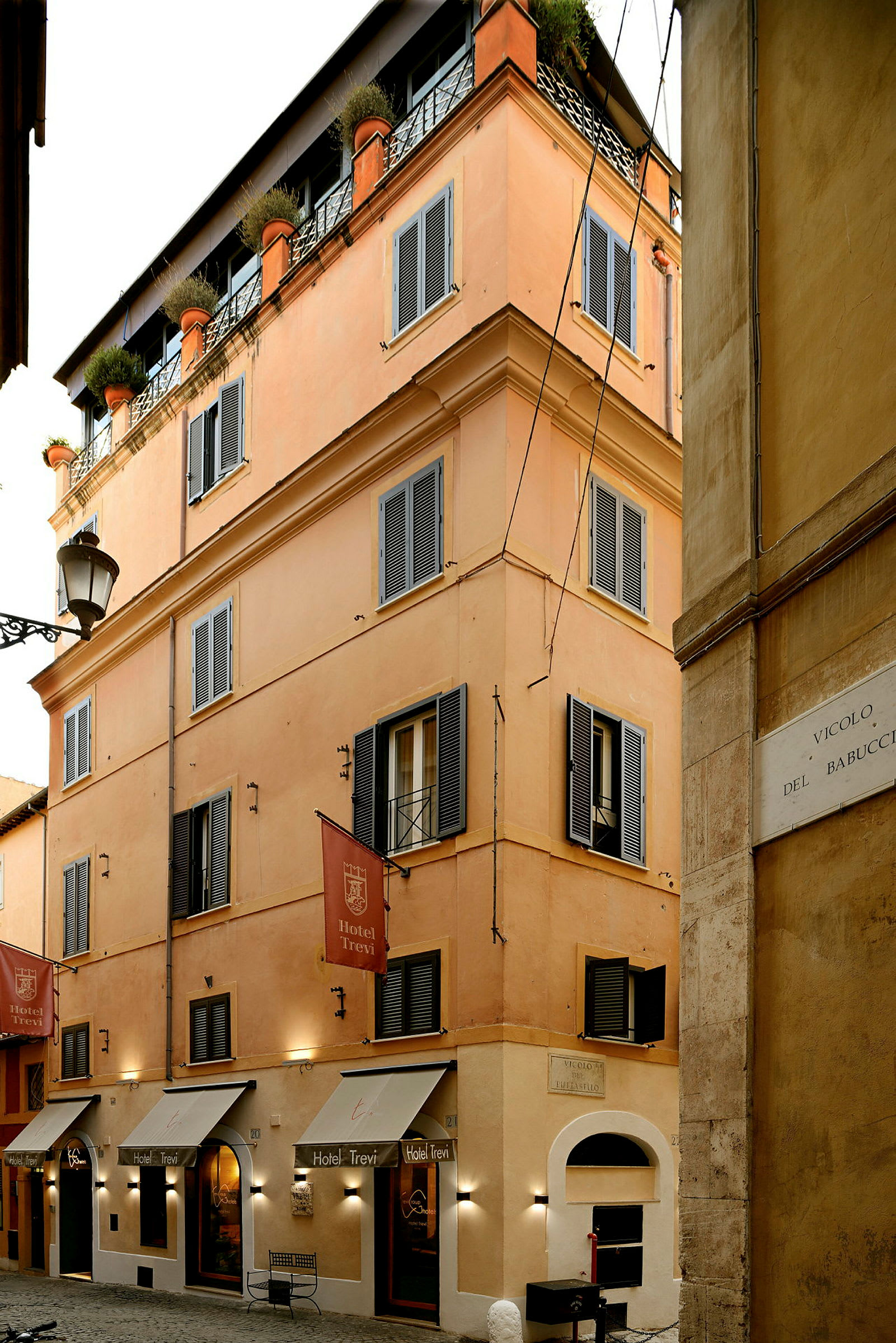 En bygning med orange facade, mørke vinduesskodder og skilte med teksten 'Hotel Trevi'. (AI-genereret tekst)