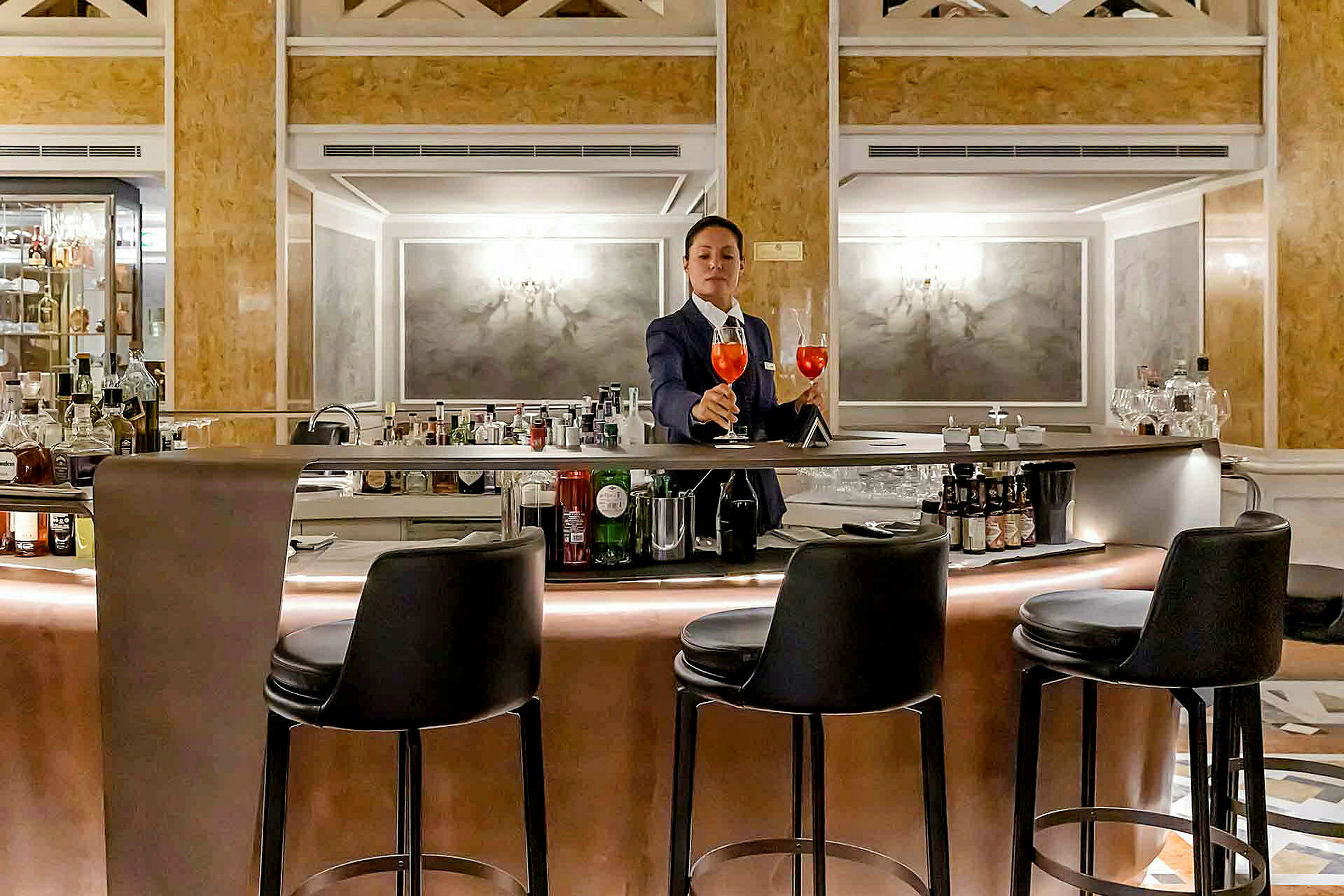 En bartender står ved en elegant bar med barstole omkring. (AI-genereret tekst)