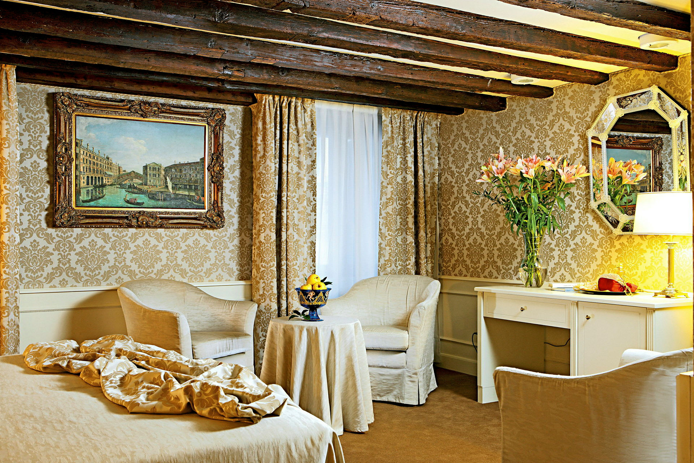 Et elegant hotelværelse med klassisk indretning inklusive to lænestole, bord, skrivebord og vægdekorationer. (AI-genereret tekst)