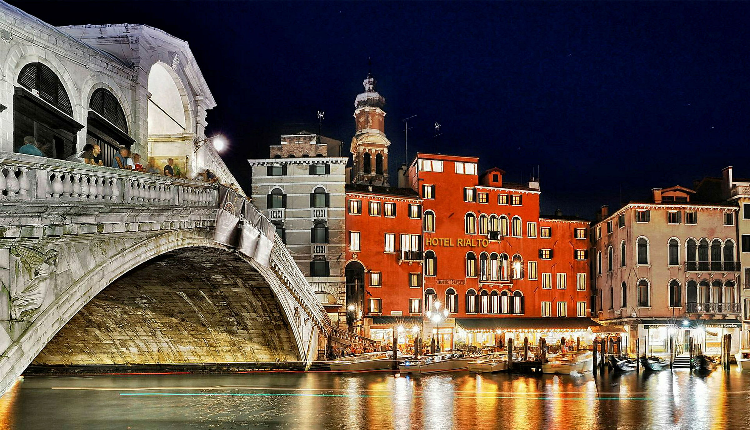 En natudsigt af Rialto-broen og nærliggende bygninger ved Grand Canal i Venedig. (AI-genereret tekst)