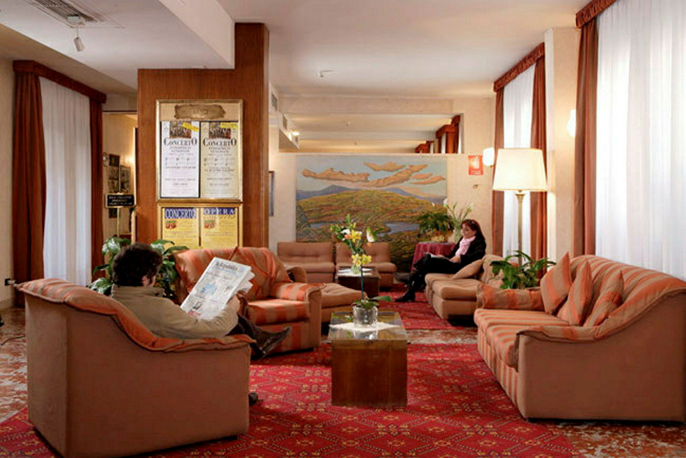 Billede af en hotellobby med sofaer og lænestole placeret på et rødt tæppe. (AI-genereret tekst)