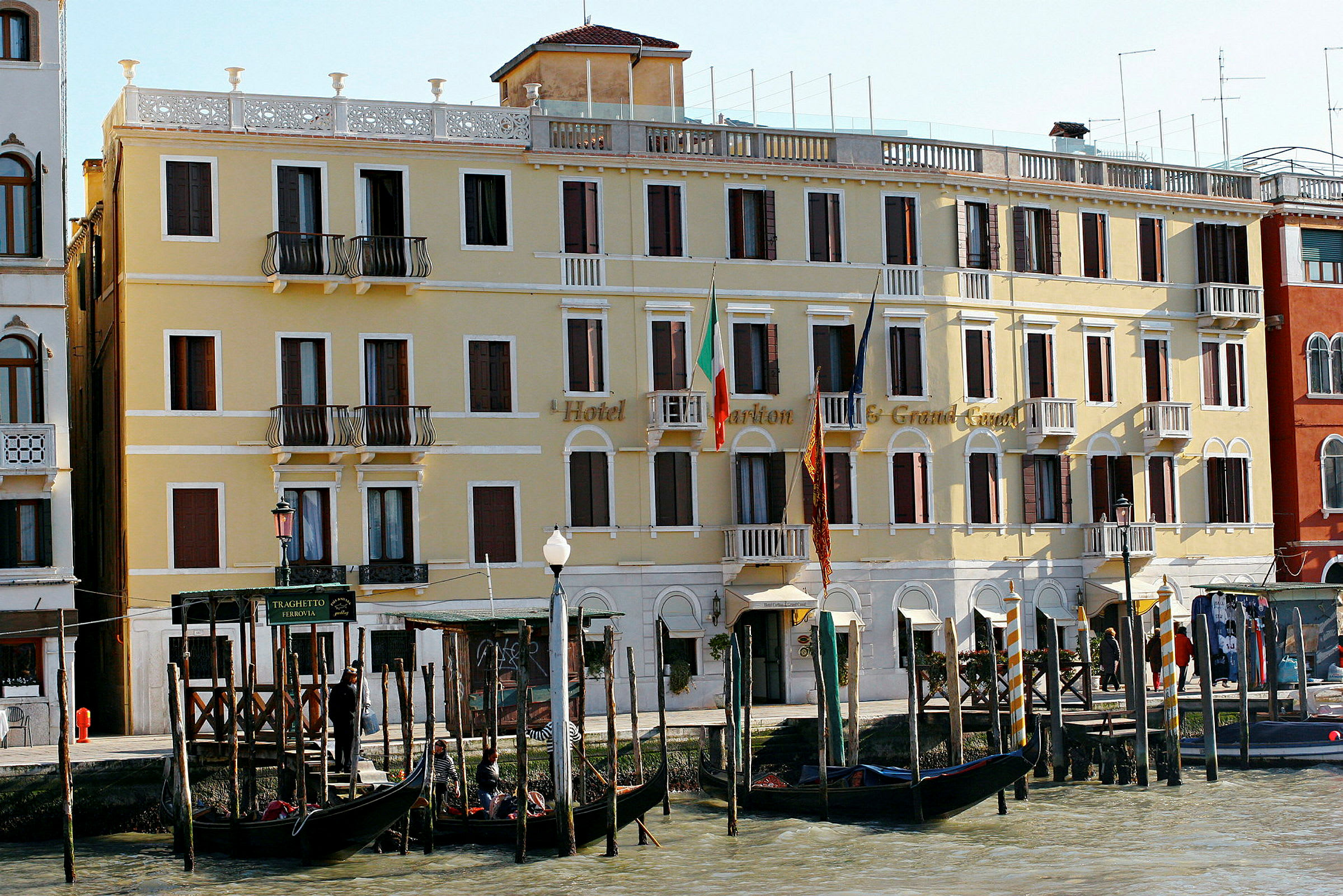 Et gult hotel ved Grand Canal i Venedig med gondoler foran. (AI-genereret tekst)