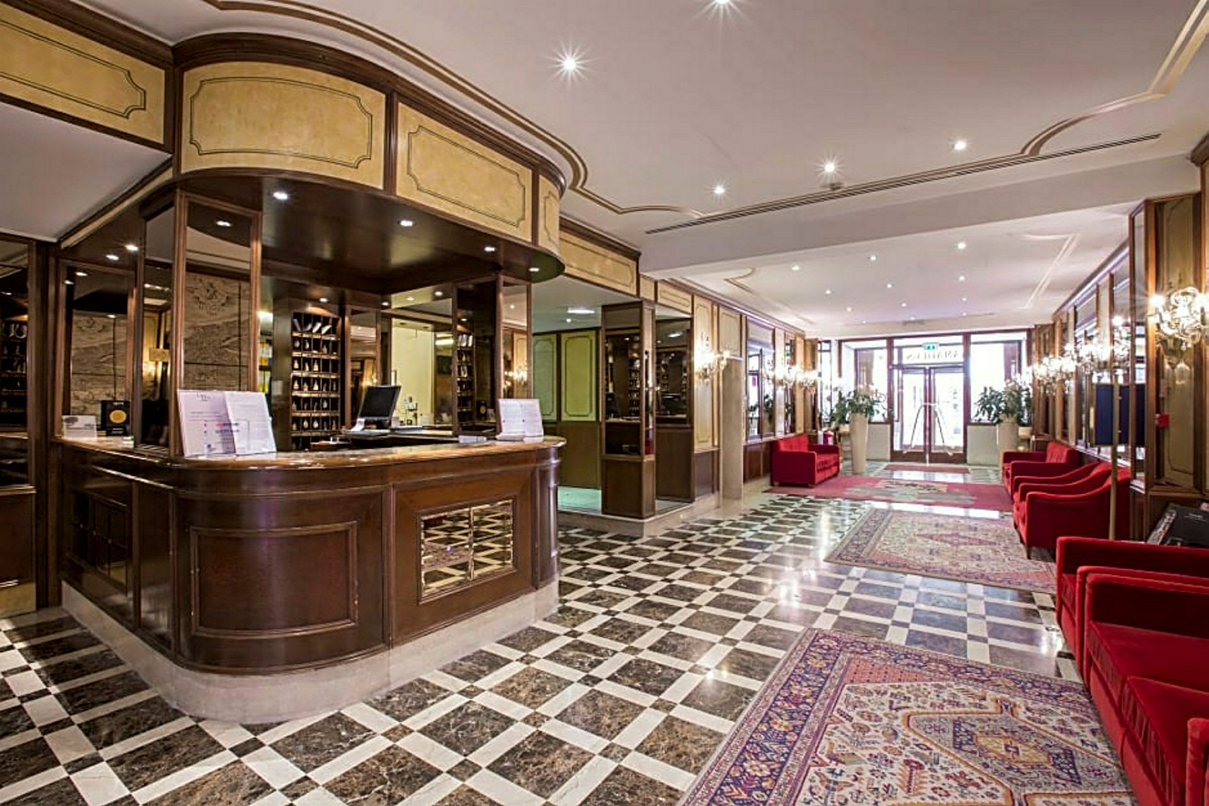 Reception og lobbyområde med marmorgulv og røde sofaer. (AI-genereret tekst)
