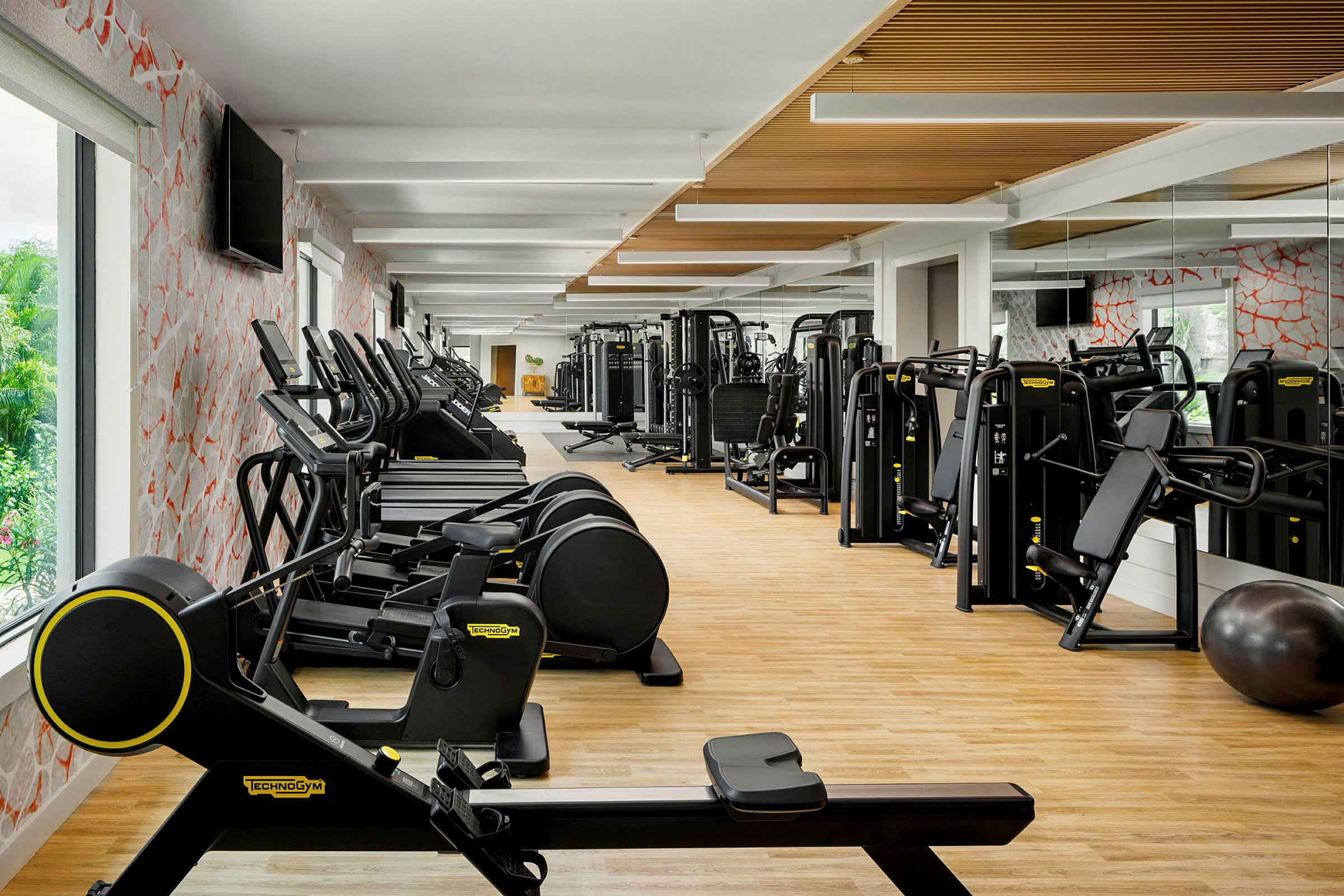 Fitnesscenter med moderne træningsmaskiner og spejlvægge. (AI-genereret tekst)