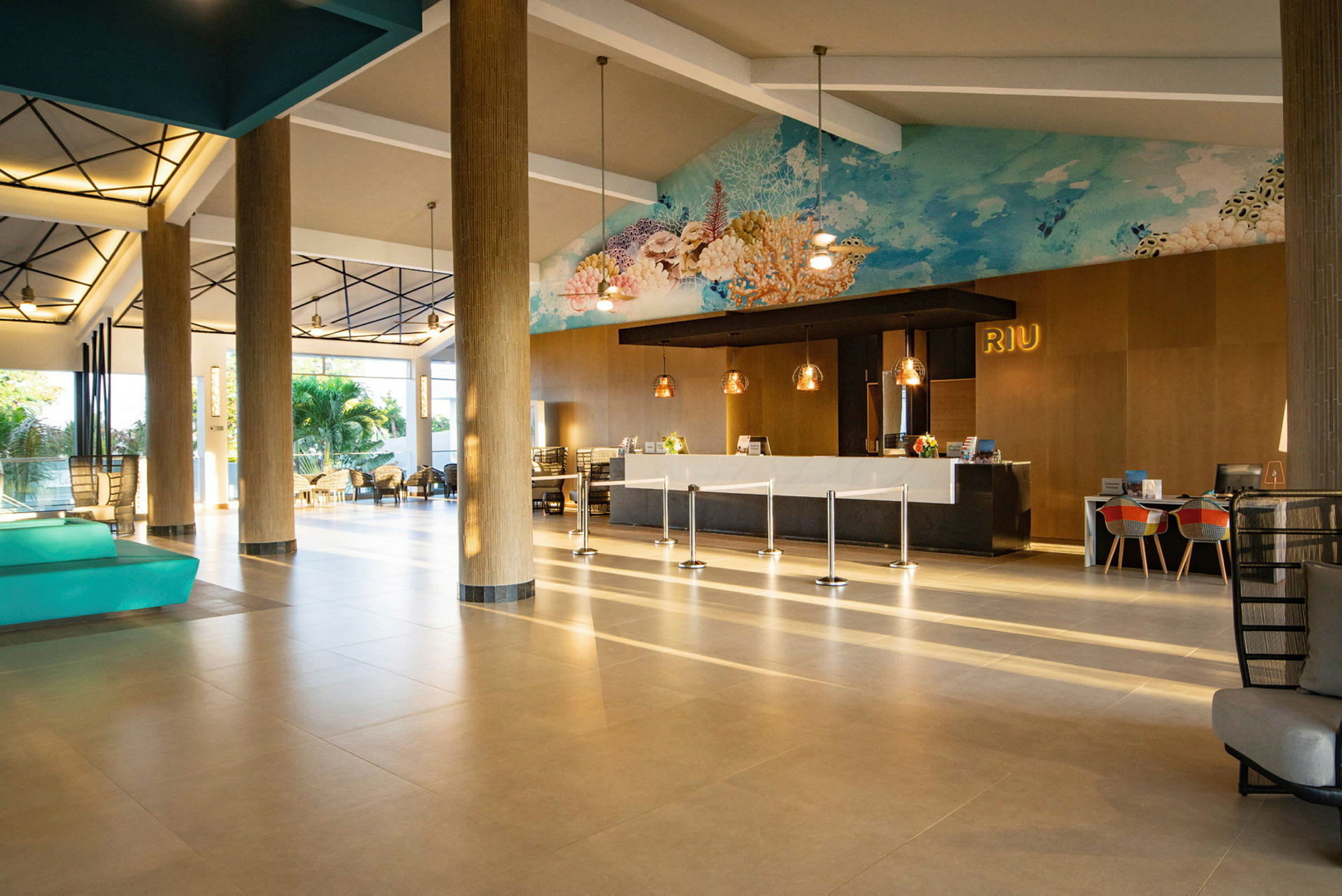 Billede af en hotellobby med lyse gulve, receptionsdisk, siddepladser og kunstværk på væggen. (AI-genereret tekst)