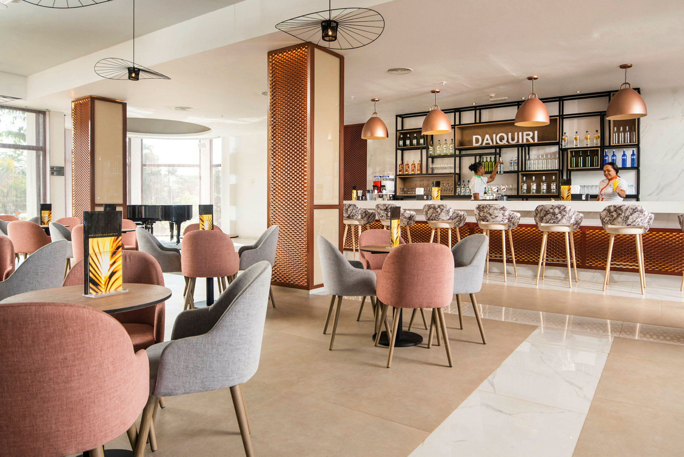 En moderne indrettet café eller bar med borde og stole i forskellige farver samt en oplyst bardisk i baggrunden. (AI-genereret tekst)