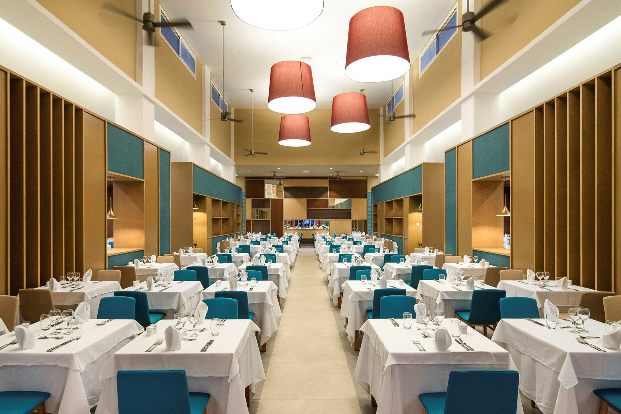 En stor og rummelig restaurant med borde dækket med hvide duge og blå stole. (AI-genereret tekst)