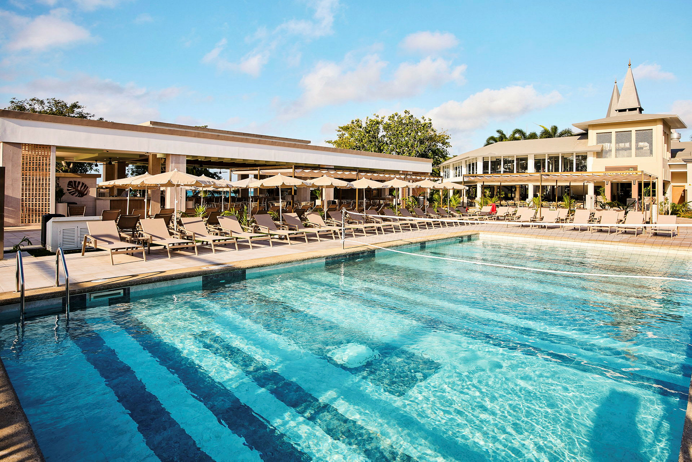 Swimmingpool med liggestole og parasoller ved et hotel. (AI-genereret tekst)