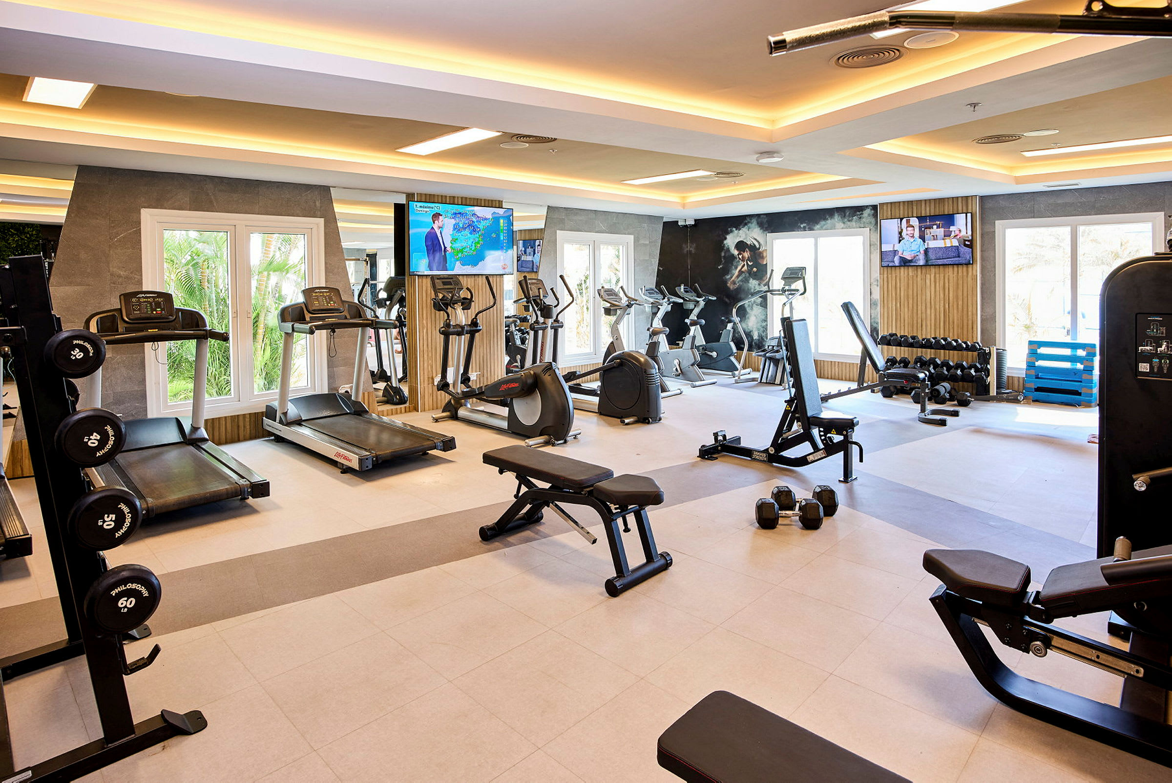 Billede af et fitnesscenter med træningsudstyr som løbebånd, motionscykler og vægte. (AI-genereret tekst)