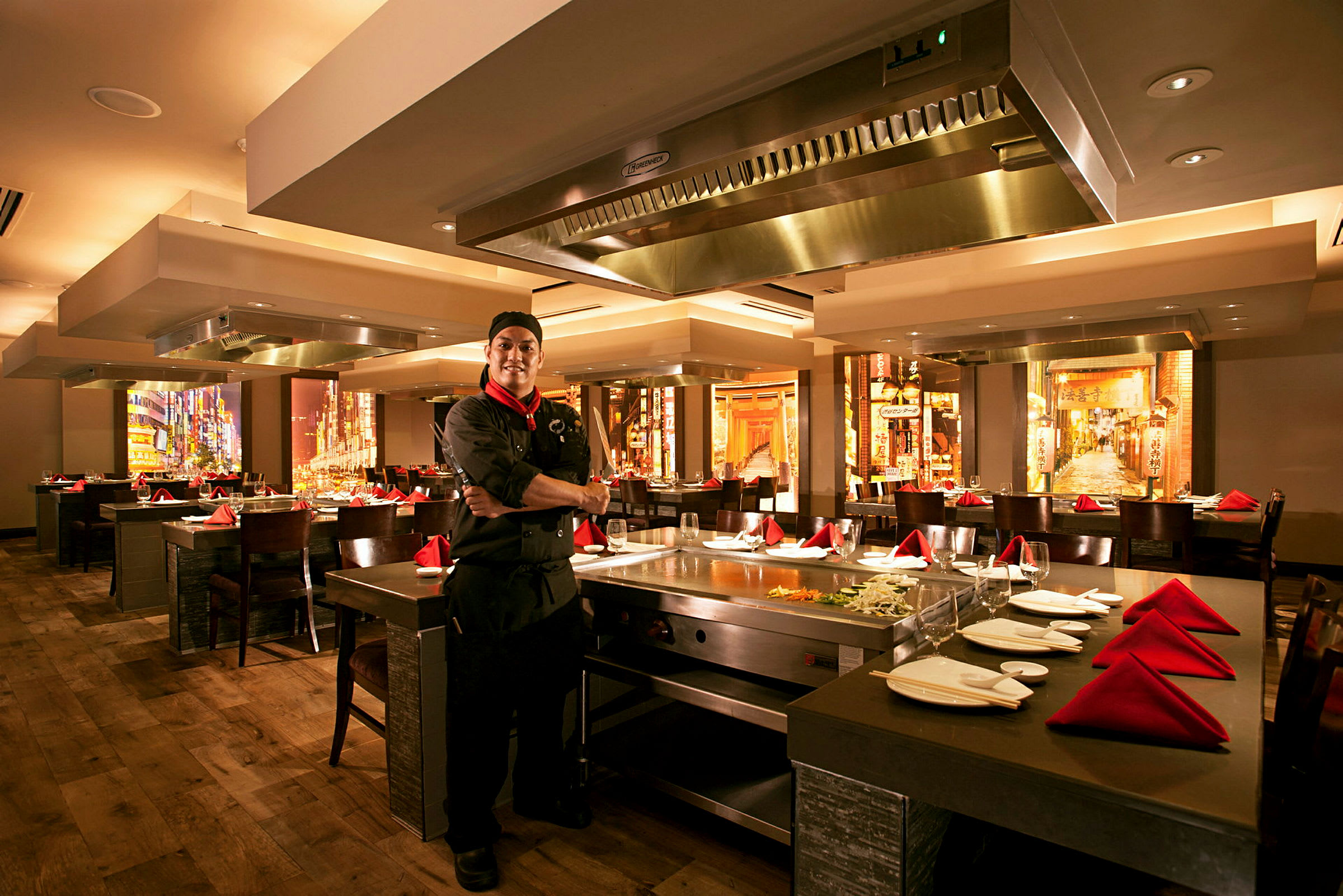 Indretning af en restaurant med opstillede borde og stole. Et teppanyaki-køkken er synligt med køkkenredskaber og ingredienser. (AI-genereret tekst)