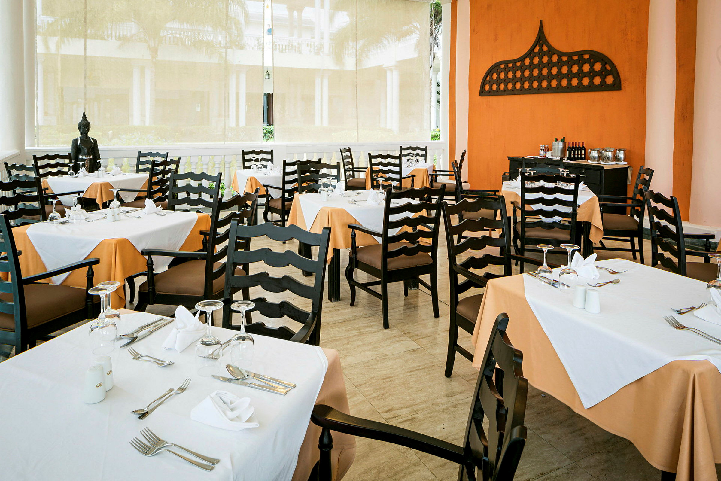 Et restaurantområde med dækkede borde og stole samt dekorationer på væggen. (AI-genereret tekst)